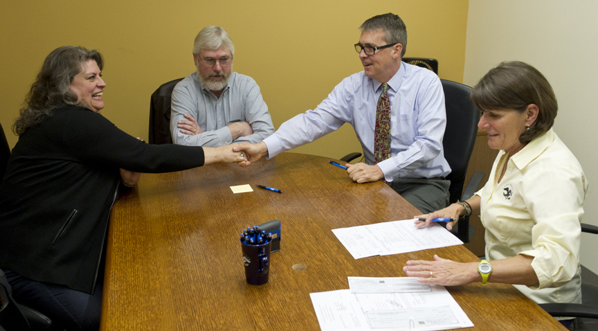 City Manager Rorie Watt, second from right, greets Tamara Rowcroft, executive director of the Alaska Housing Development Corporation, left, and Stephen Sorensen, president of AHDC's Board of Directors, as they meet to sign title papers at First American Title with Colleen Sullivan on Friday for the sale of two lots in the new Renninger Subdivision. AHDC is planning on building about 30 affordable housing units on the new land made available by the city.