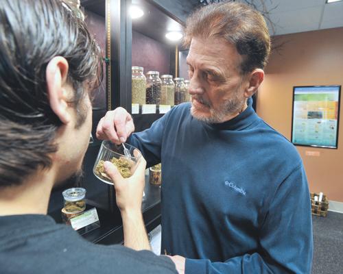 Theodore Alex Bastia, Jr. examines pot before making a purchase at Breeze Botanicals, Oct. 1 in Ashland, Oregon. Marijuana shops in the state began selling marijuana last Thursday for the first time to recreational users.