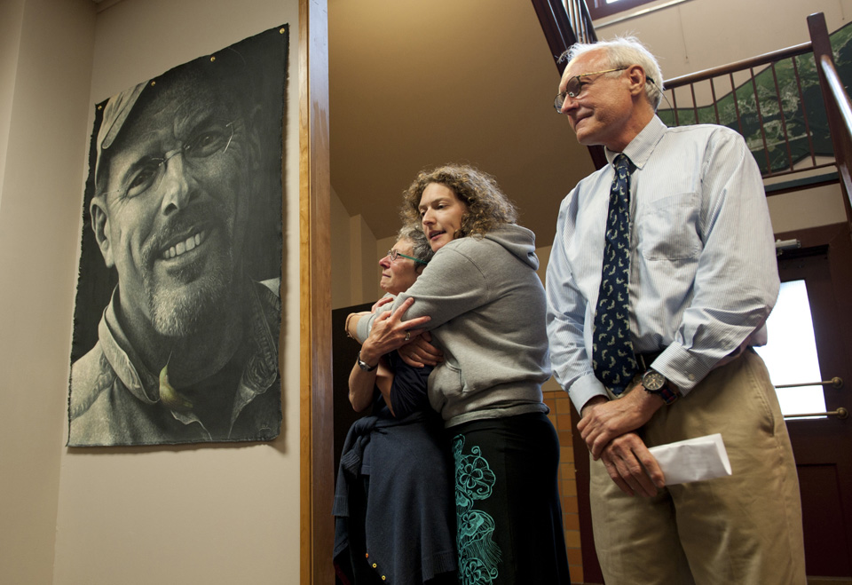 Libby Stortz is comforted by her daughter, Sasha, after unveiling a portrait of her husband, William, Thursday Aug. 18, 2016, at City Hall. William Stortz was working as city building inspector when he was killed in the Aug. 18, 2015, Kramer Avenue landslide. City Administrator Mark Gorman, at right, a close friend of the Stortzes, spoke at the unveiling, congratulating Sitkan Norm Campbell for leading a project to build a display wall in three days. Artist Steve Lawrie spoke about painting the lifelike portrait.