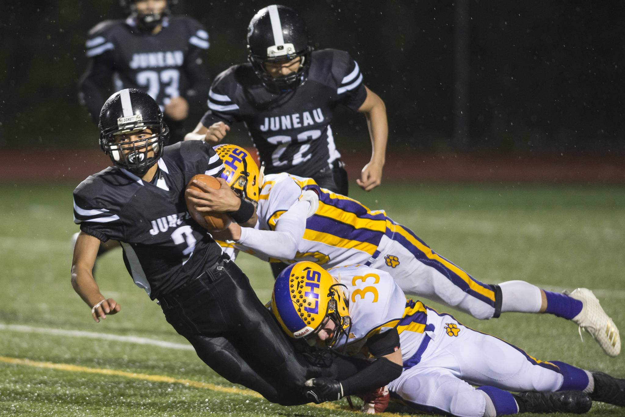 Juneau United’s Luis Mojica is tackled by Lathrop’s Bubba Maschmeier, top, and Josiah Opp at Thunder Mountain High School on Saturday. (Michael Penn | Juneau Empire)