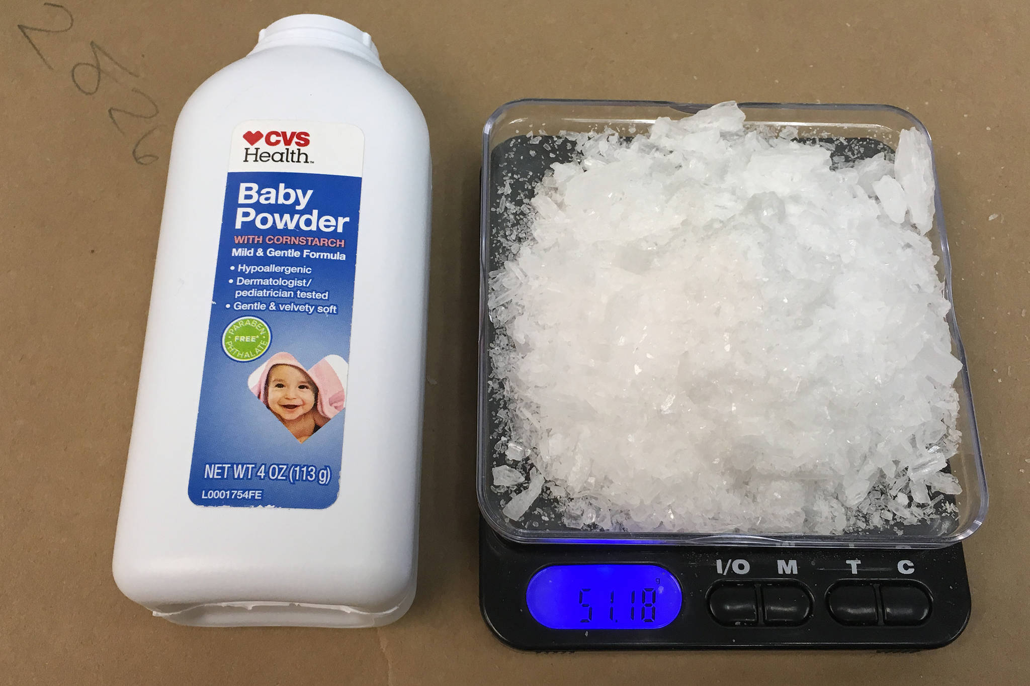 Methamphetamine seized by law enforcement sits next to a bottle of baby powder for scale. (Courtesy Photo | Department of Public Safety)