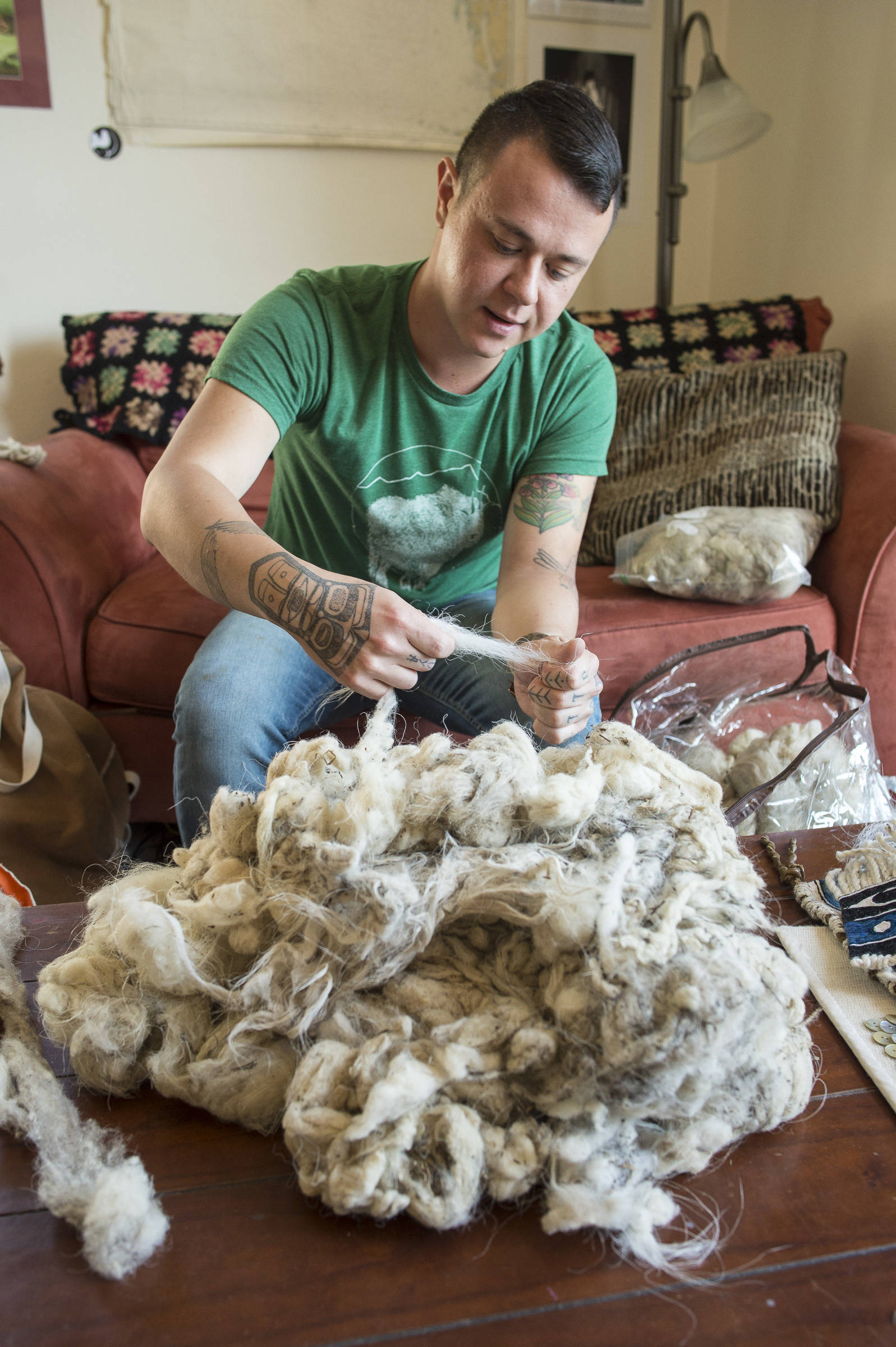 Chilkat weaver Ricky Tagaban pull guard hairs from raw mountain goat fur at his apartment in Juneau on Monday, Sept. 10, 2018. Tagaban said friends collect the fur in the spring when goats lose their winter coat. Tagaban turns the material into wool warp with a cedar bark core ready for his weaving projects or to sell to other weavers. (Michael Penn | Juneau Empire)
