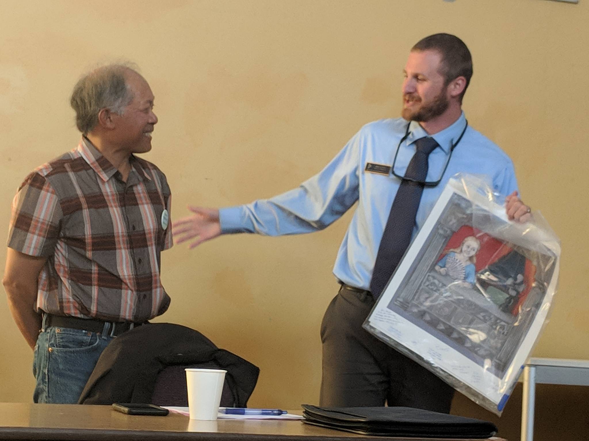 Juneau Arts & Humanities Council Board Vice President Bing Carrillo gifts a piece of art to departing Board President Eric Scott during the JAHC annual meeting. Scott had served as president for three years and said he was feeling loss and melancholy. (Ben Hohenstatt | Capital City Weekly)