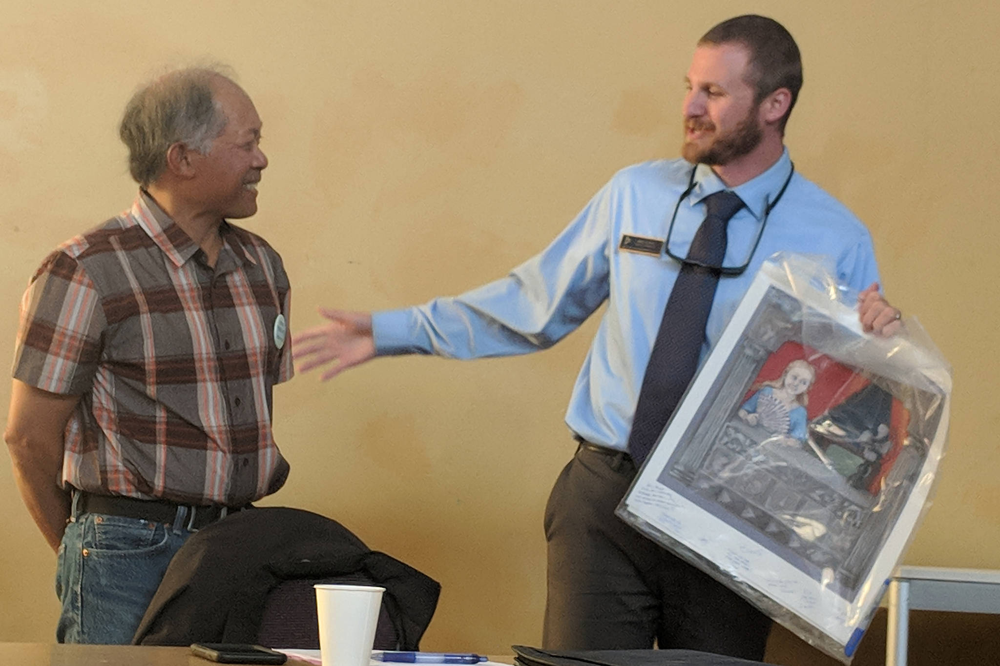 Juneau Arts & Humanities Council Board Vice President Bing Carrillo gifts a piece of art to departing Board President Eric Scott during the JAHC annual meeting. Scott had served as president for three years and said he was feeling loss and melancholy. (Ben Hohenstatt | Capital City Weekly)