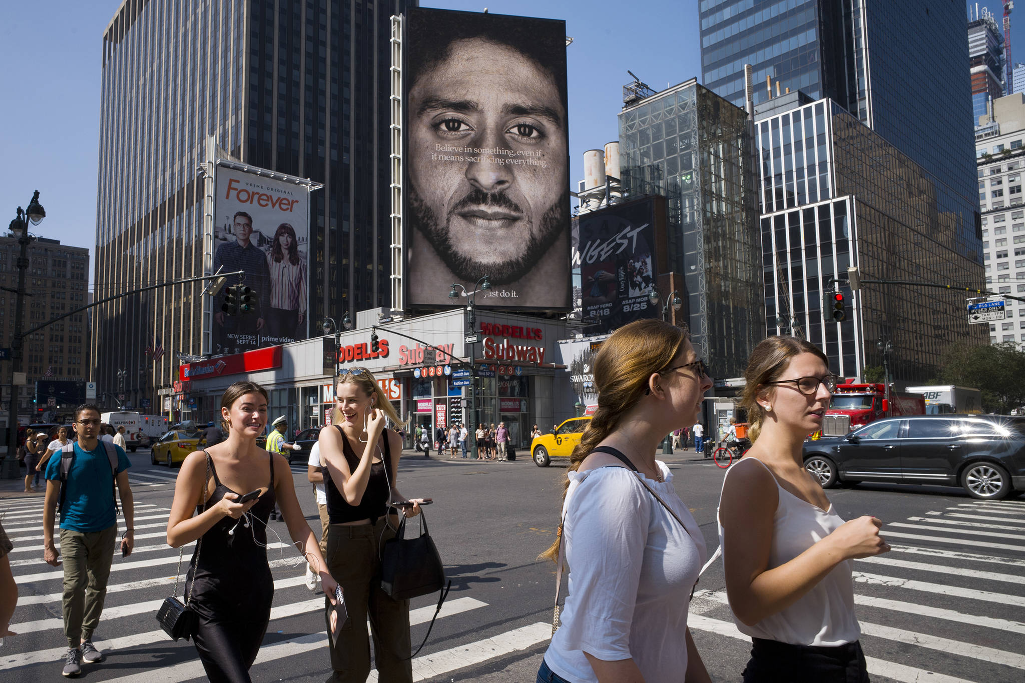In this Sept. 6, 2018, file photo, people in New York walk past a Nike advertisement featuring former San Francisco 49ers quarterback Colin Kaepernick, known for kneeling during the national anthem to protest police brutality and racial inequality. In response to Nike’s support of Kaepernick, the Rhode Island town of North Smithfield is considering asking its departments to refrain from purchasing Nike products. (AP File Photo | Mark Lennihan)