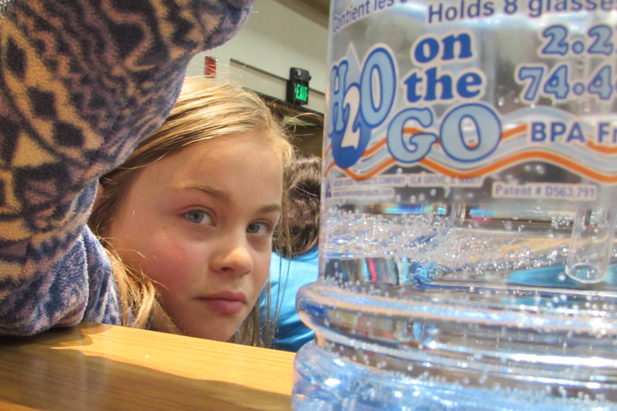 Lola Brown, 10, watches closely as a siphon pump and length of hose empties one jug of water into a jug sitting on the floor. Introduce a Girl to Engineering Day included time at six different stations, and each station introduced science and engineering principles with experiments. (Ben Hohenstatt | Capital City Weekly)