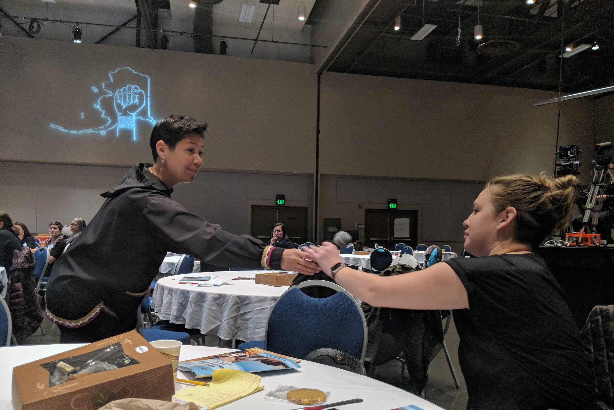 Ayyu Qassataq, Vice President for First Alaskans Institute passes a microphone to Adrianne Christensen of Port Heiden, who was in Juneau for a two-day social justice summit FAI hosted at Centennial Hall. (Ben Hohenstatt | Capital City Weekly)