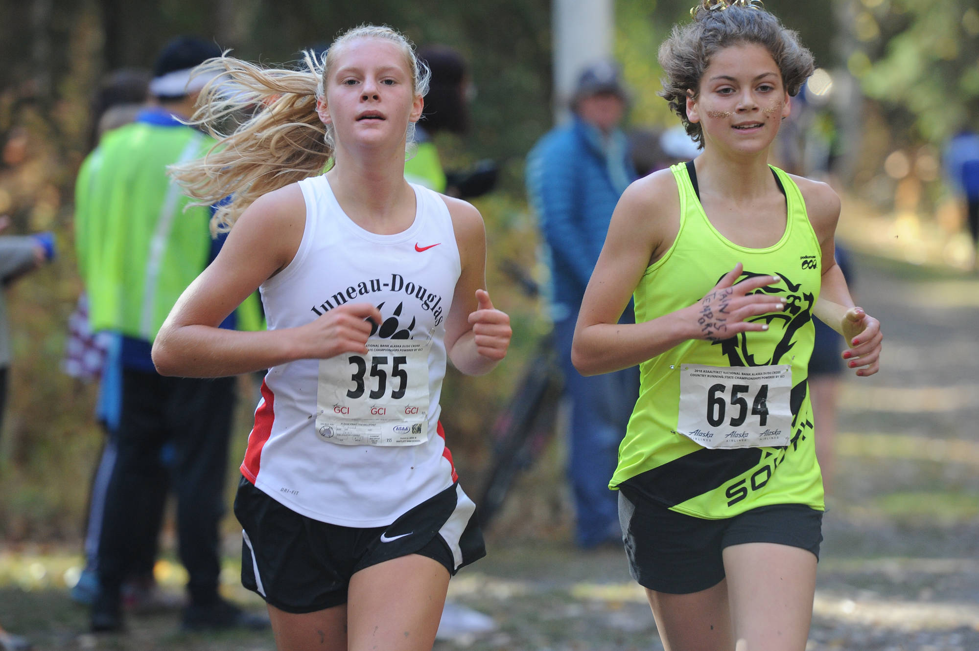 Juneau-Douglas’ Sadie Tuckwood leads South Anchorage’s Ava Earl in the ASAA/First National Bank Alaska Division I girls state cross country meet at the Bartlett High School running trails on Saturday. (Michael Dinneen | For the Juneau Empire)