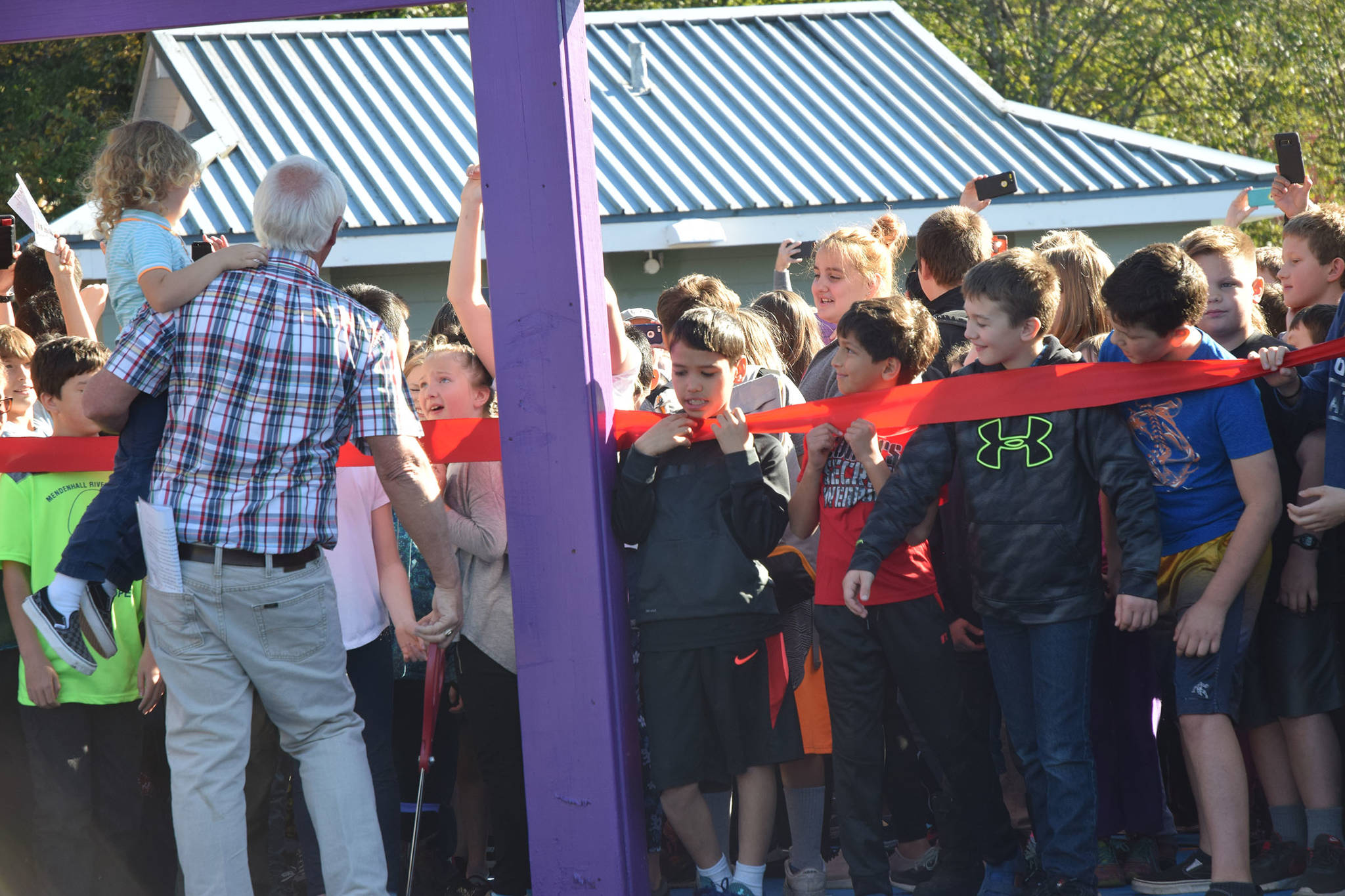 Children wait for Mayor Ken Koelsch to cut a ribbon at the entrance to Project Playground on Saturday at Twin Lakes. (Kevin Gullufsen | Juneau Empire)