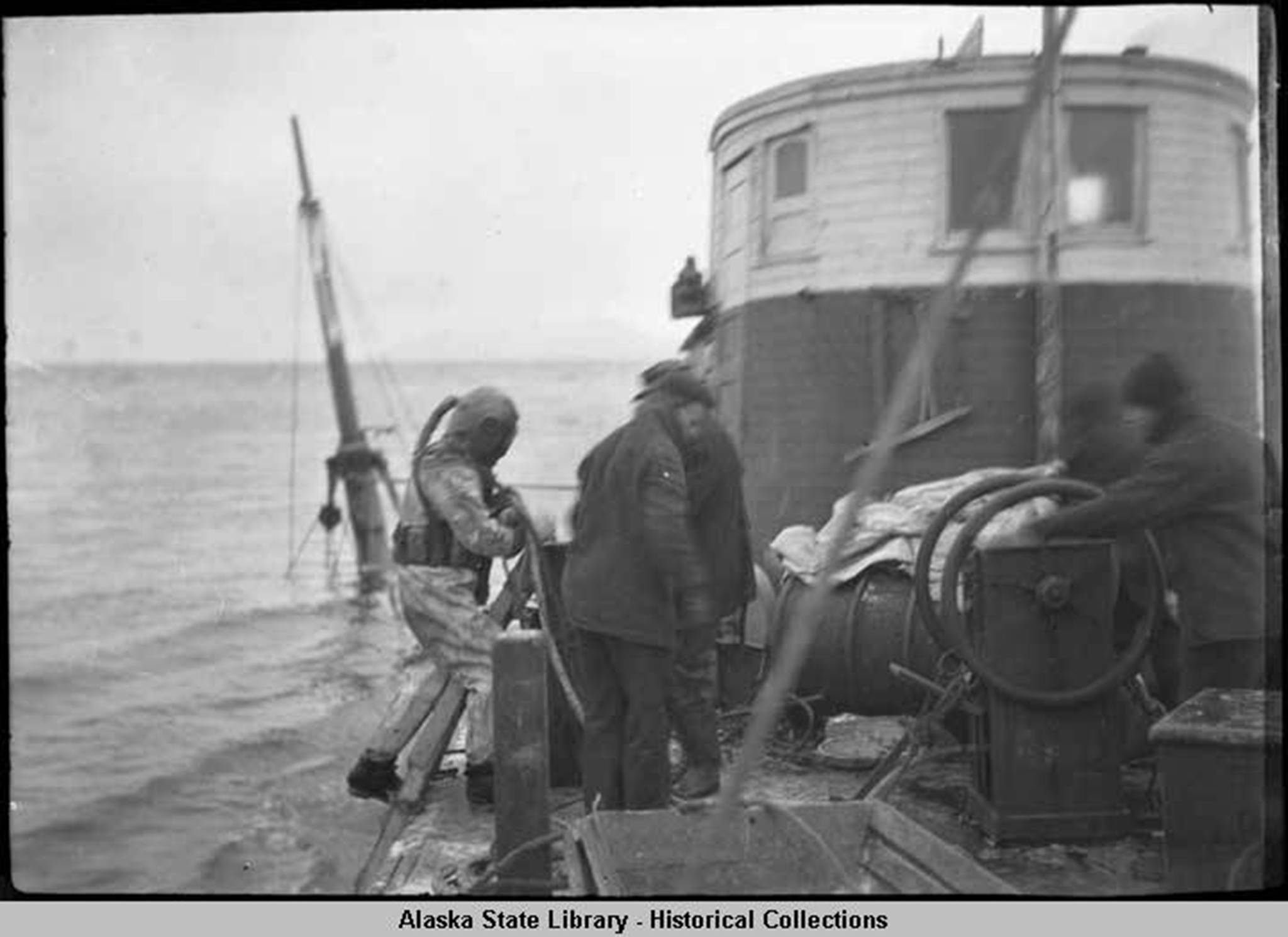 Diver and workers on boat above sunken Princess Sophia, 1918. (Alaska State Library Historical Collection, ASL-P87-1710)