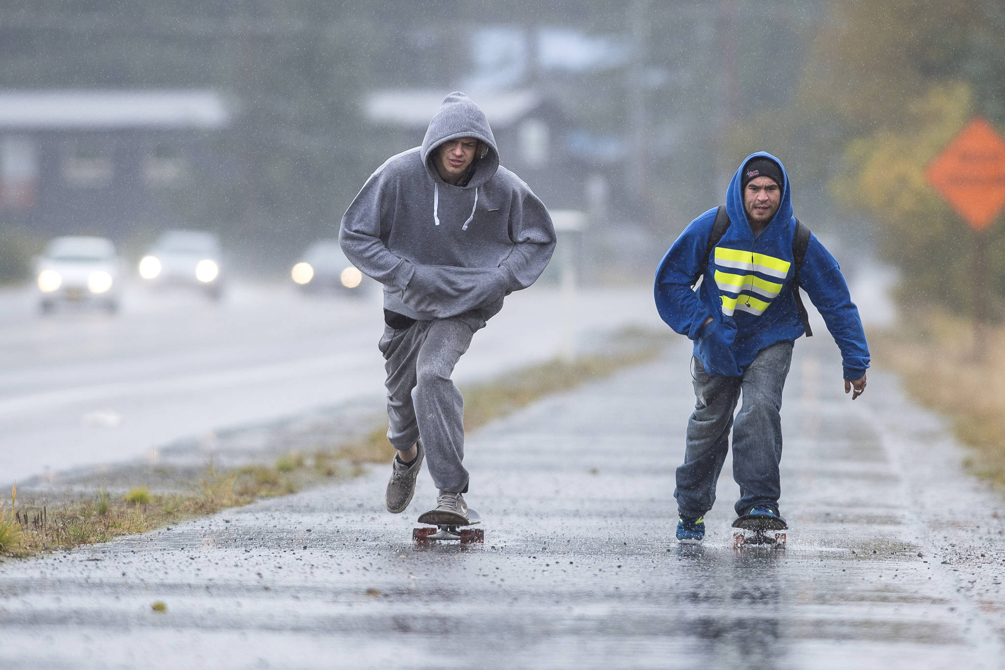 Domanic Quick, left, and Ben Kinser travel by skateboard through the rain along Egan Drive on Tuesday, Sept. 25, 2018. The National Weather Service is calling for periods of rain on Wednesday with a high near 55. (Michael Penn | Juneau Empire)