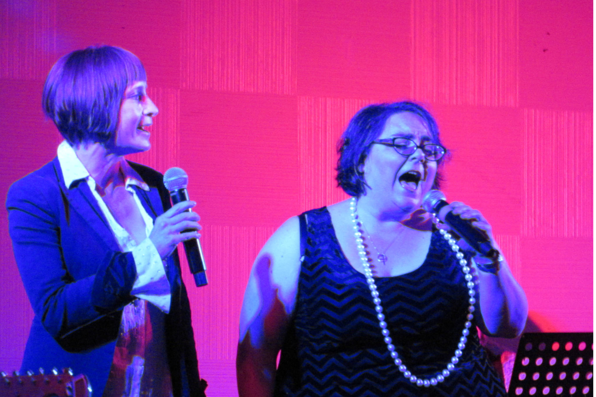 Susan Lewandowski and Collette Costa harmonize on stage during the Red Light Revue. Costa said on stage the pair have been singing together for decades and her friend traveled from Seattle to perform Saturday night. (Ben Hohenstatt | Capital City Weekly)