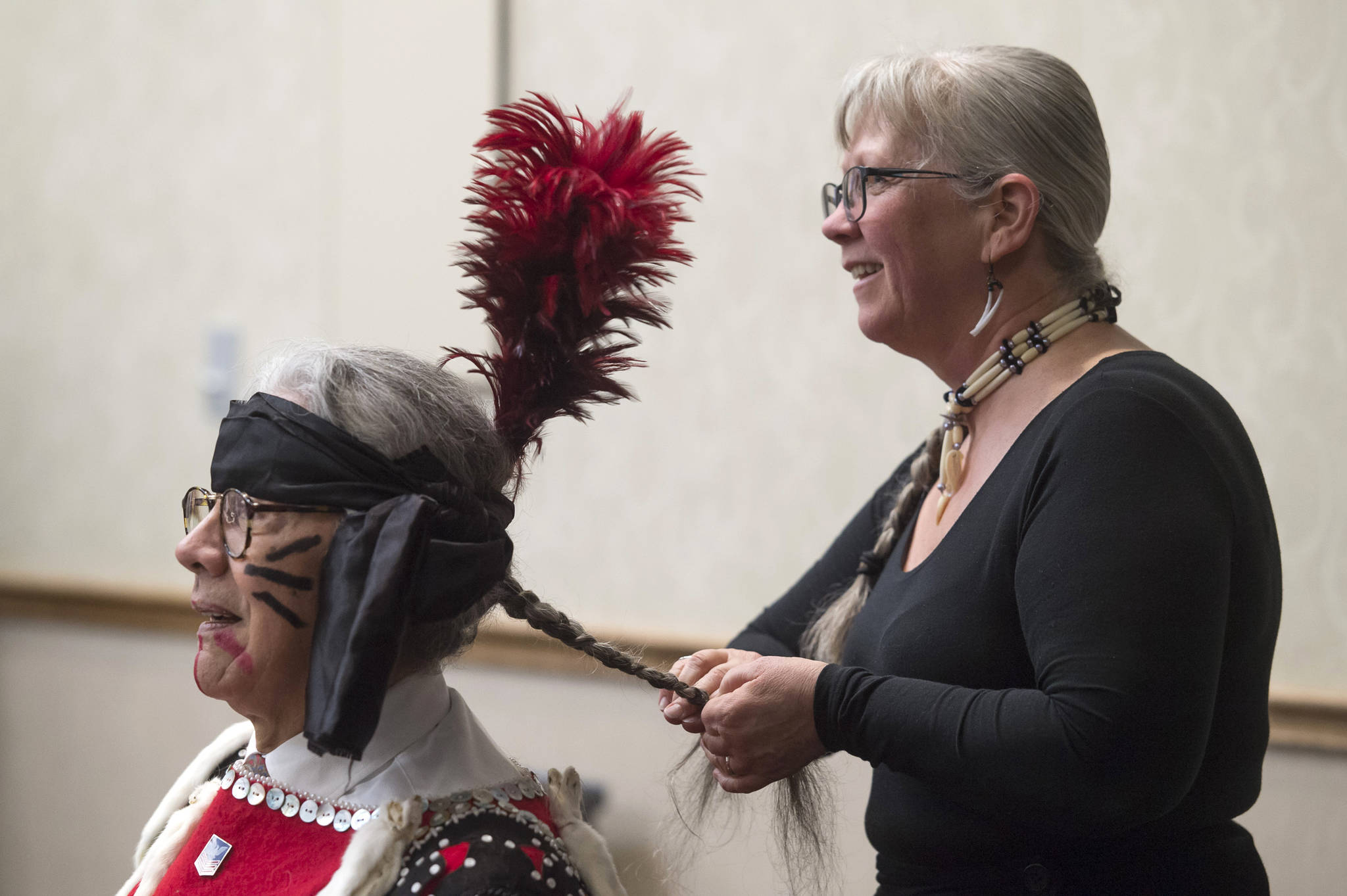 Michelle Rochette braids Walter Soboleff Jr.’s hair before their group, the Yees Ku Oo Dancers, perform during Indigenous Peoples Day celebrations at the Elizabeth Peratrovich Hall on Monday, Oct. 8, 2018. (Michael Penn | Juneau Empire)