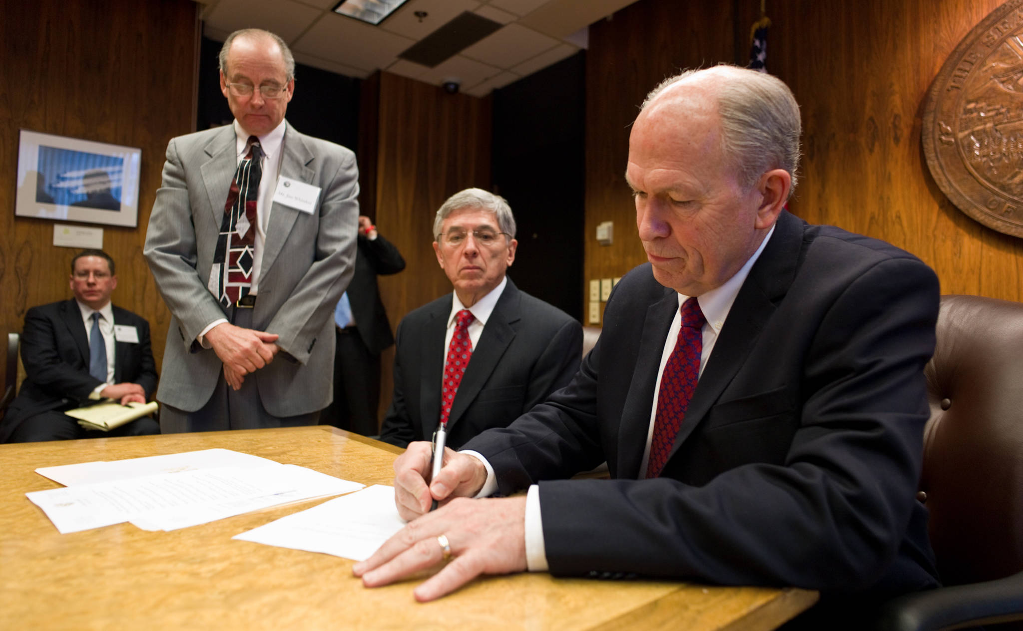 Gov. Bill Walker, right, signs transitional papers in front of Lt. Gov. Byron Mallott, center, and Walker’s Chief of Staff, Jim Whitaker, at the Capitol. Walker and Mallott were sworn into office just hours before.