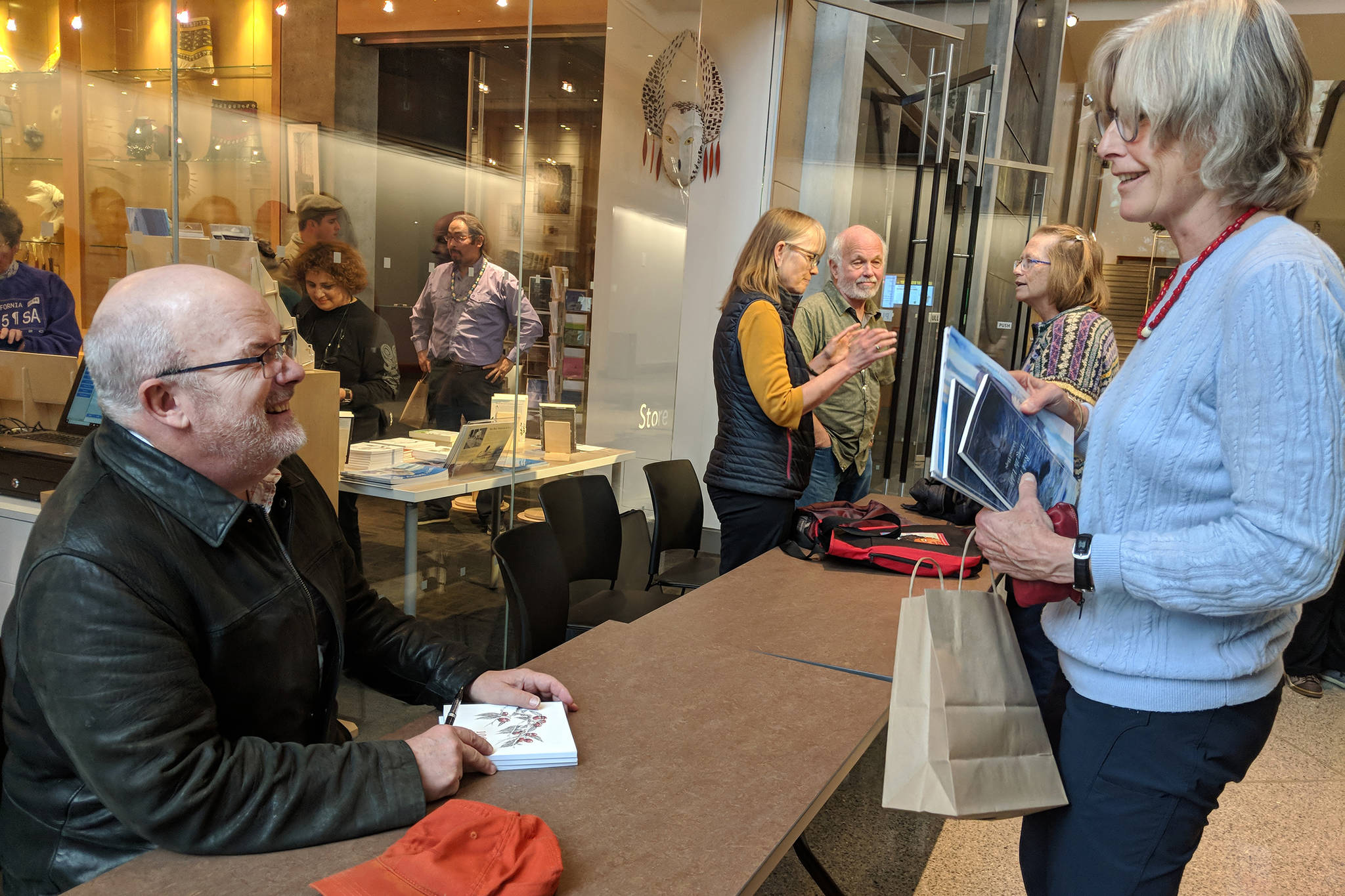 Author John Straley prepares to sign a book for author Heather Lende after the Alaska Literary Festival at the Father Andrew P. Kashevaroff building. They were both speakers at the event. (Ben Hohenstatt | Capital City Weekly)