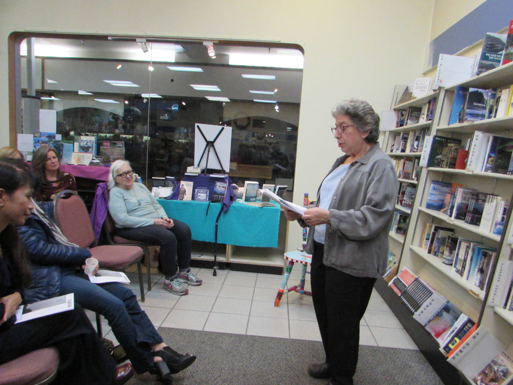 Margo Waring reads her work to a crowd at Hearthside Books. In the front row, fellow writers Mary Lou Spartz and Miriam Wagoner Listen. (Ben Hohenstatt | Capital City Weekly)