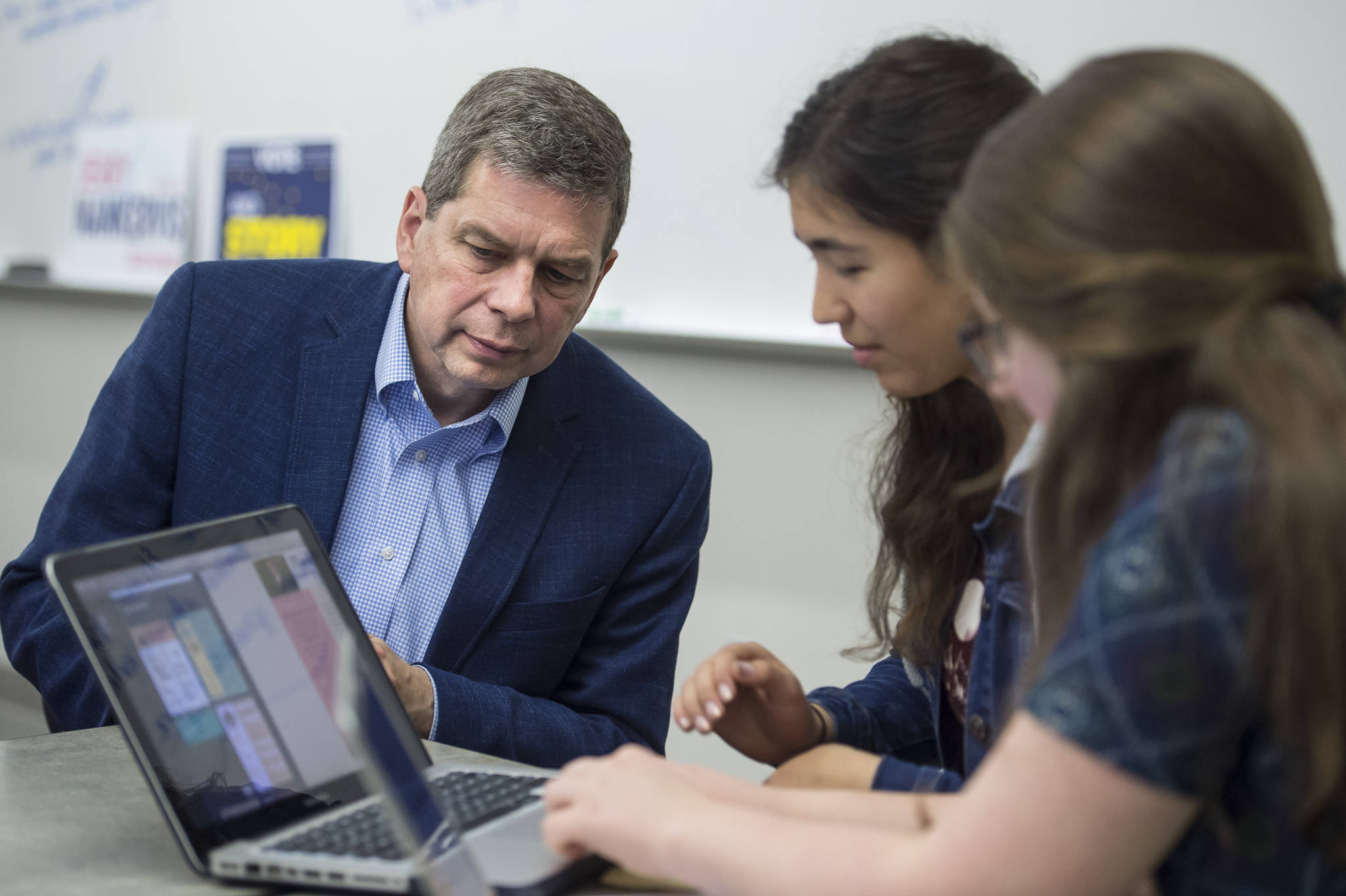 Democratis gubernatorial candidate Mark Begich watches as Thunder Mountain High School senior students Tristan Weissmuller, center, and Briannah Letter work on a candidate voter page during their government class on Friday, Oct. 26, 2018. (Michael Penn | Juneau Empire)