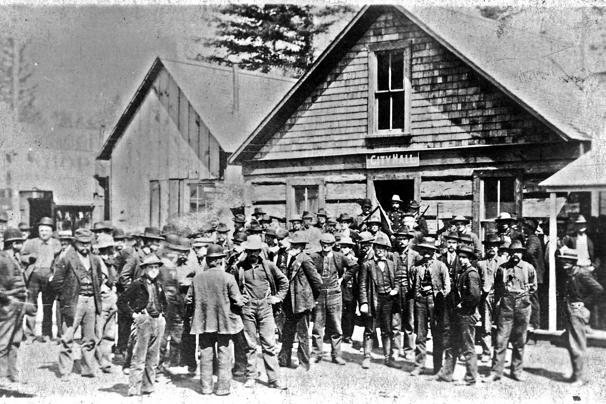 This is the only known photograph we have of the interior of Skagway’s First City Hall during its time period as the town’s city hall. George A. Brackett with his long beard is seated on the immediate right. Brackett was the builder of the Brackett Wagon Road that ran from Skagway to White Pass City. Based on the presence of Brackett, it is possible that this picture represents the start or finish of negotiations between Brackett and the White Pass & Yukon Route railroad over the purchase of the Brackett Wagon Road by the railroad. (National Park Service, Klondike Gold Rush National Historical Park, Brackett Family Collection, BFC/CBD 156; KLGO PB-38-6237)
