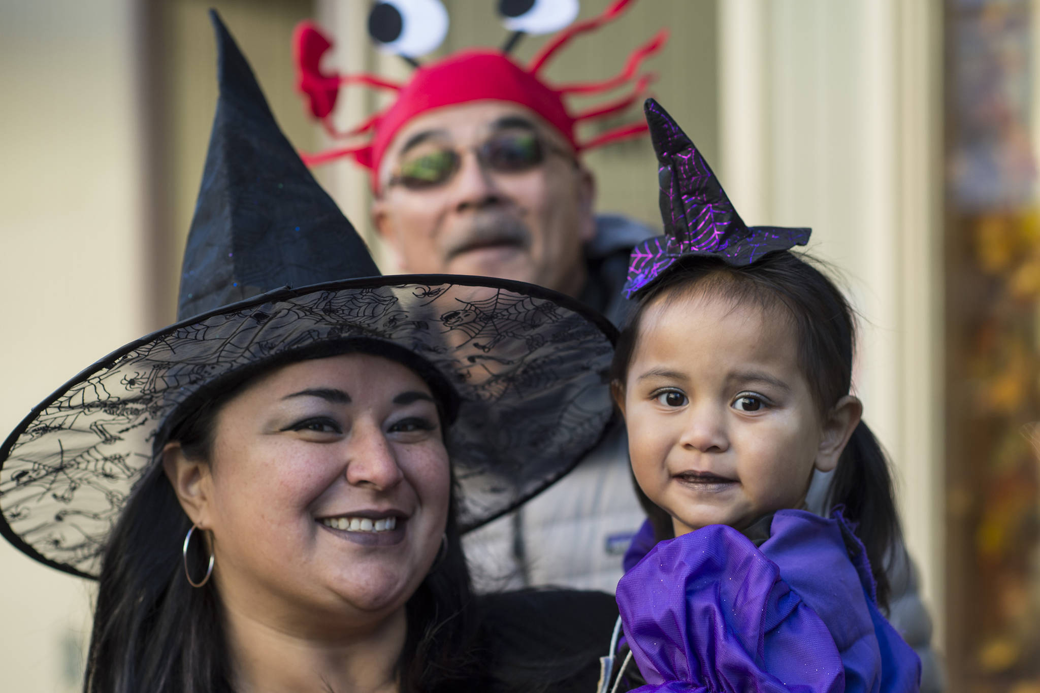 Shakira Vallejo holds her daughter, Gabriela, 3, as father and grandfather, Patrick Vallejo, photo bombs their picture while visiting merchants downtown for Halloween on Wednesday, Oct. 31, 2018. For the fourth year Kindred Post has organized the Halloween celebration for trick-or-treaters. (Michael Penn | Juneau Empire)