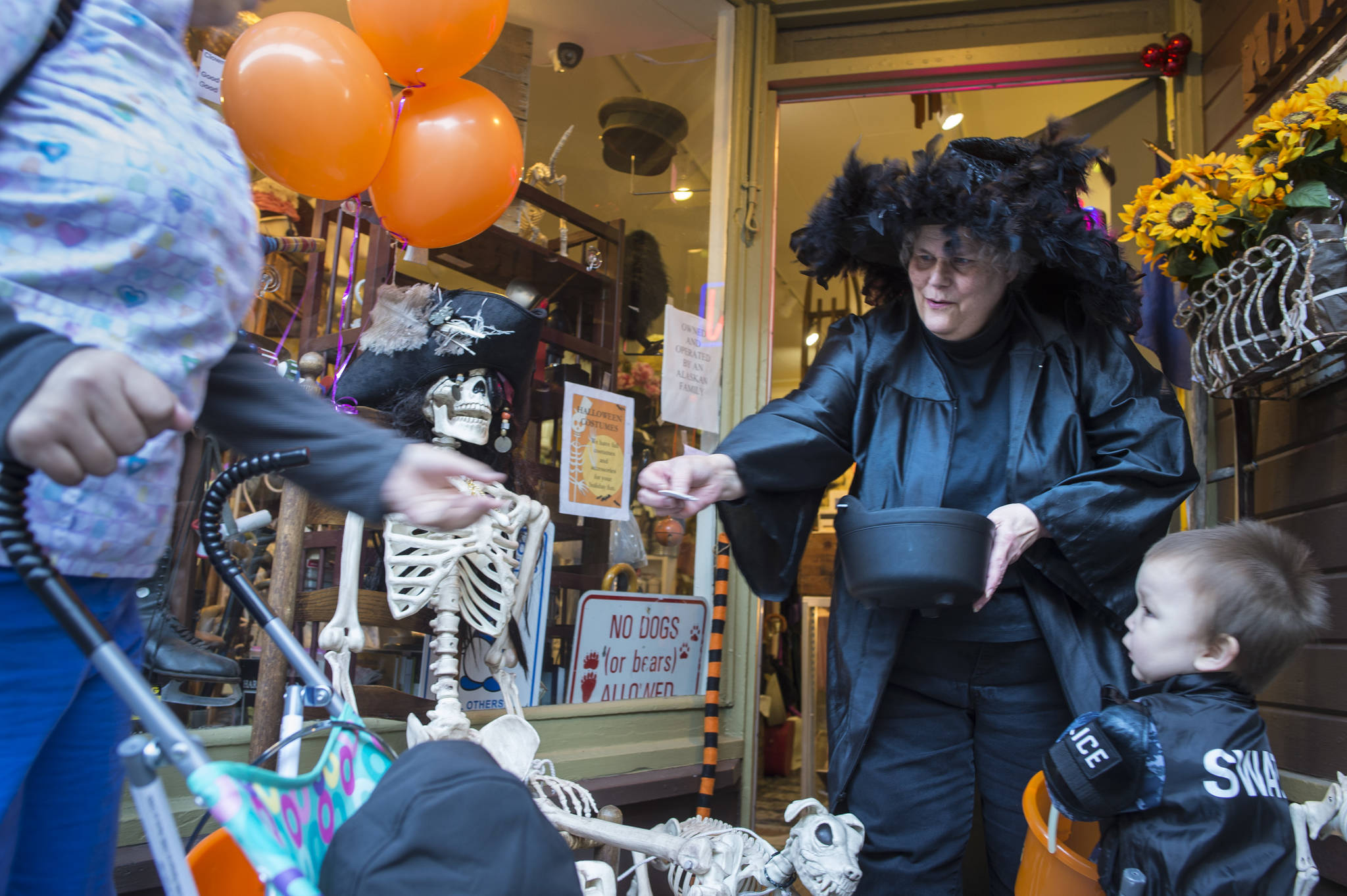 Suzanne Hudson, owner of Nana’s Attic, hands out candy to visiting children and their parents on Wednesday, Oct. 31, 2018. For the fourth year Kindred Post has organized the Halloween celebration for trick-or-treaters. (Michael Penn | Juneau Empire)