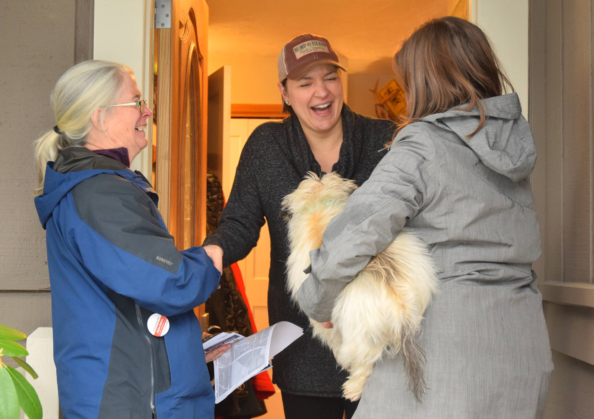 Alaska labor commissioner Heidi Drygas reacts after opening her front door to find Alaska’s indpendent Congressional candidate, Alyse Galvin, on Sunday, Nov. 4, 2018. Galvin is holding Drygas’ dog. (James Brooks | Juneau Empire)