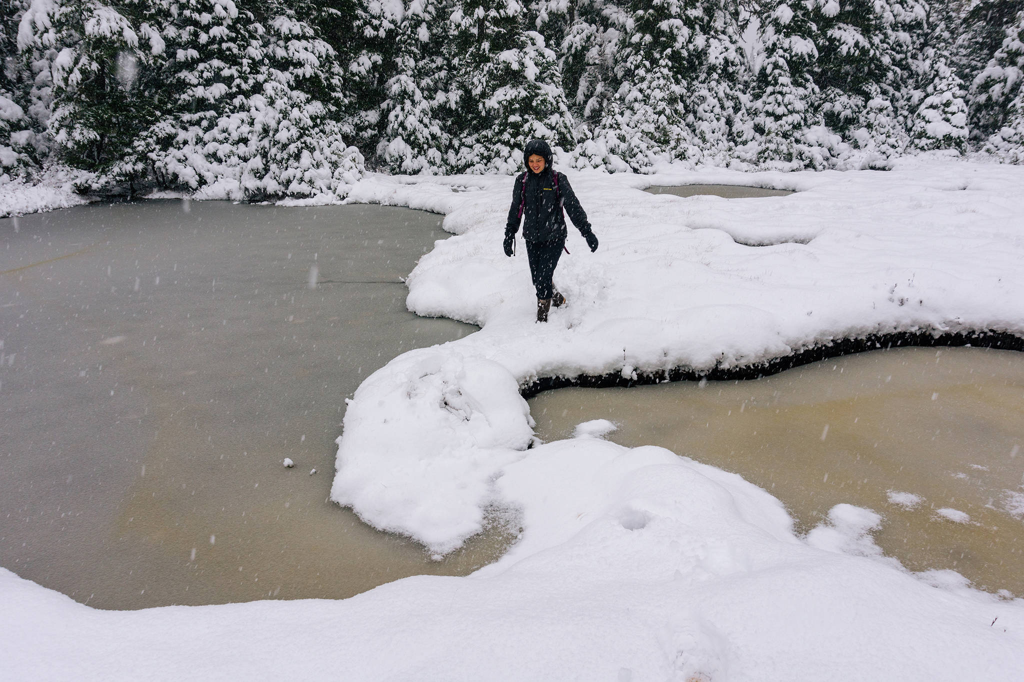 Claire Helgeson attempts to cross between two snow covered ponds. (Gabe Donohoe | For the Juneau Empire)