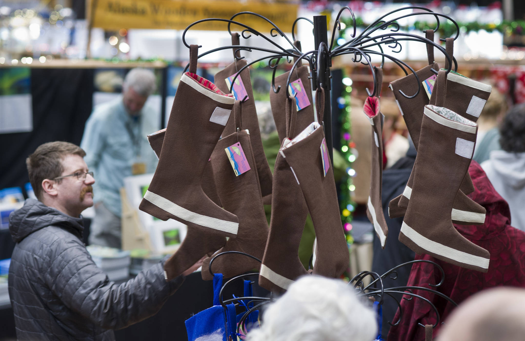 Tyler Thomas takes a peak at Barbara Mitchell’s brown boot stockings on display at Public Market in Centennial Hall on Friday, Nov. 25, 2016. (Michael Penn | Juneau Empire File)