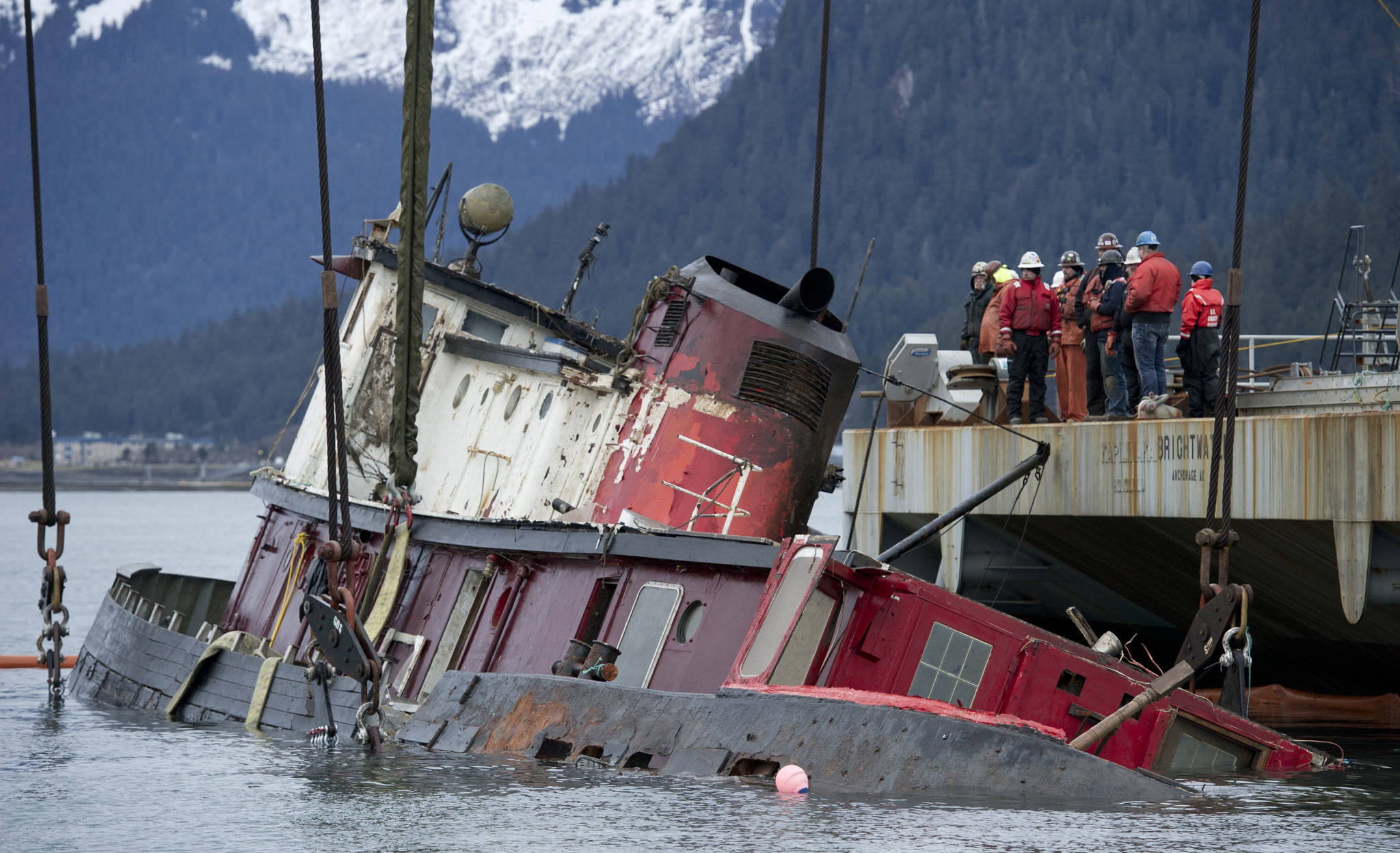 Crew aboard the barge-crane Brightwater lifts the sunken 96-foot tugboat Challenger in Gastineau Channel in February 2016. The federal government has filed a civil lawsuit against Juneau artist R.D. Robinson, alleging he is responsible for the cost of removing the ship from Gastineau Channel. (Michael Penn | Juneau Empire file)