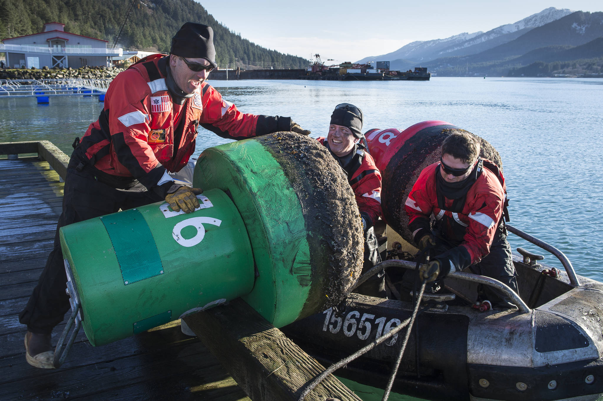 Andrew Tetrault, left, Kevin McManus, center, and Carl Sporleder from the U.S. Coast Guard Cutter Elderberry, a buoy tender based in Petersburg, lift a buoy onto the dock at the Wayside Park on Channel Drive on Monday, Nov. 5, 2018. The 19 buoys that mark the passage through the Mendenhall Bar were taken out for the season. (Michael Penn | Juneau Empire)