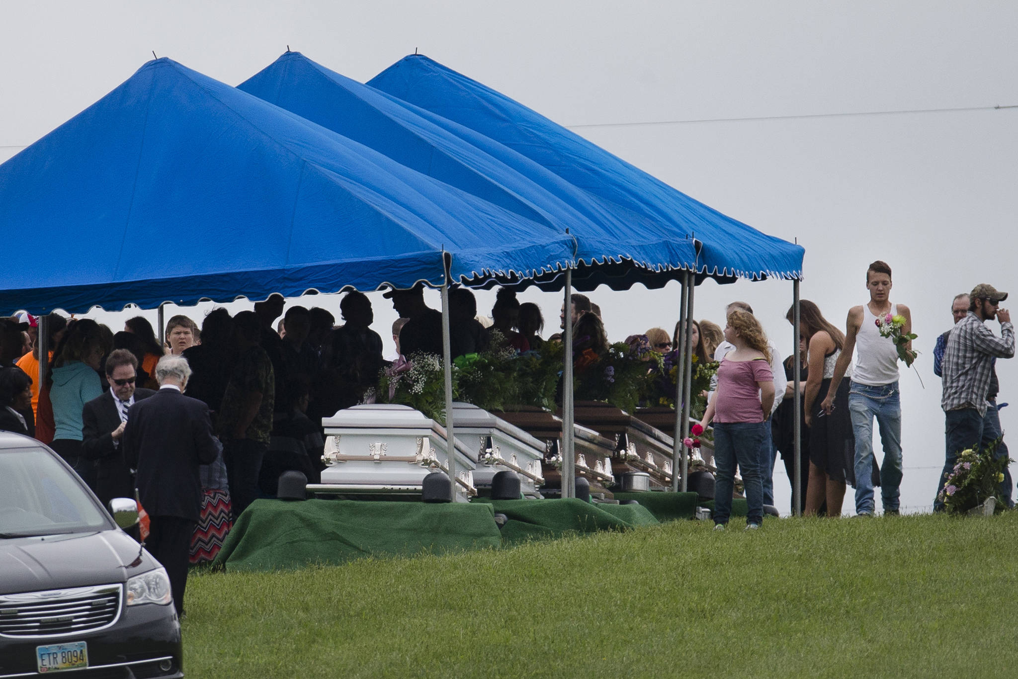 In this May 3, 2016 photo, mourners gather around caskets for six of the eight members of the Rhoden family found shot April 22, 2016, at four properties near Piketon, Ohio, during funeral services at Scioto Burial Park in McDermott, Ohio. Authorities said Tuesday, Nov. 13, 2018, that a family of four has been arrested in in the slayings of eight members of one family in rural Ohio two years ago. (John Minchillo | Associated Press File)