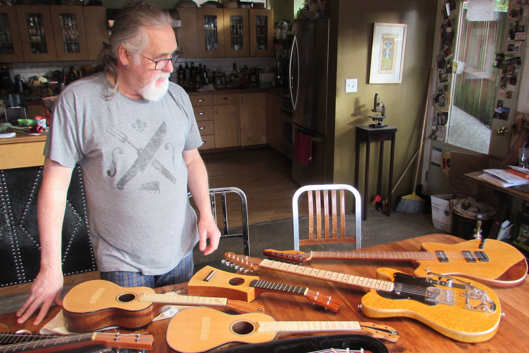 Paul Gardinier looks at a fleet of stringed instruments he’s made over the better part of the past decade at his home in Juneau on Nov. 16, 2018.(Ben Hohenstatt | Capital City Weekly)