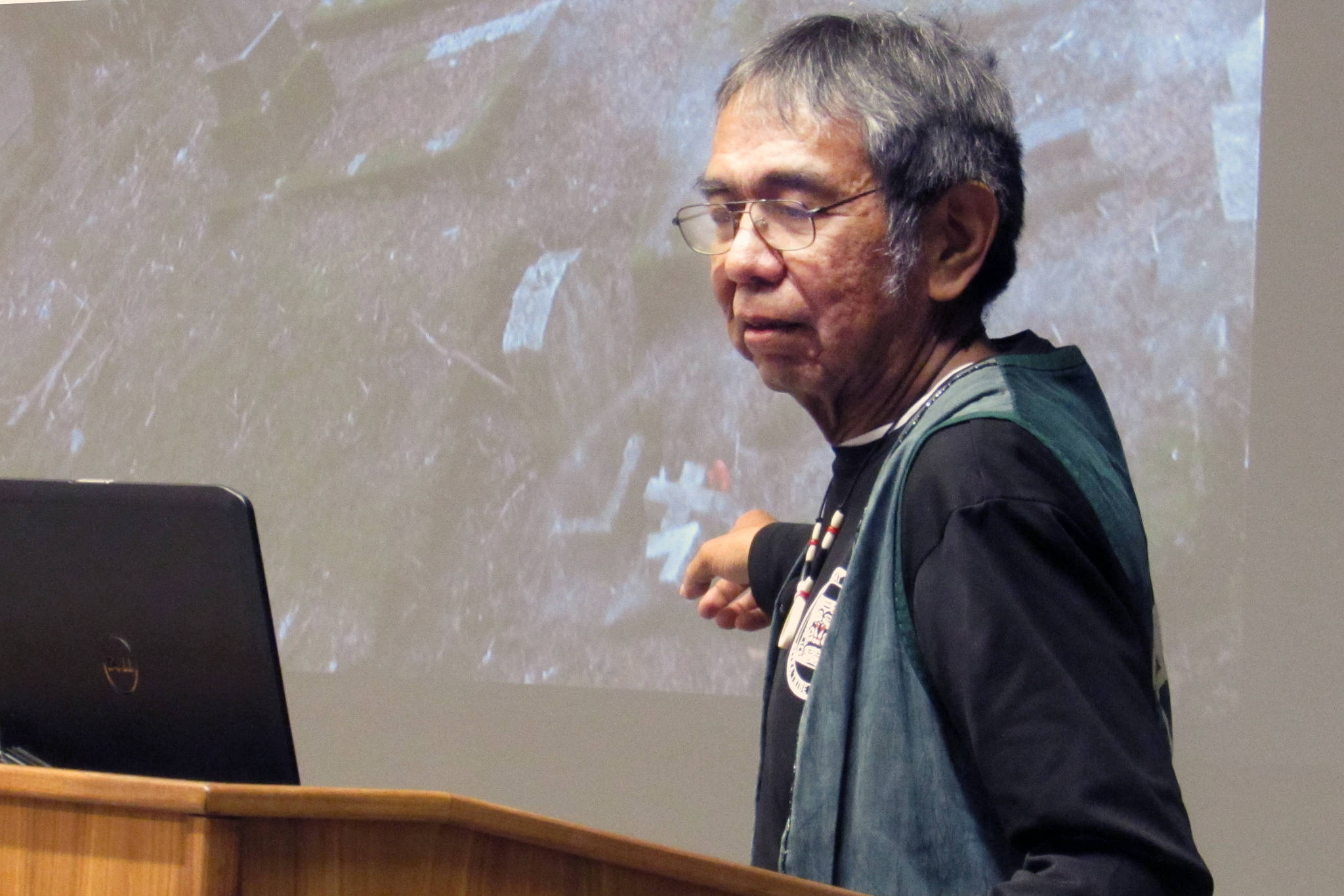Bob Sam points to a photo of a Sitka cemetery during his Evening at Egan lecture Friday, Nov. 16 at University of Alaska Southeast’s Egan Library. Sam spoke about the importance of respecting ancestors and shared stories of his efforts to do so. (Ben Hohenstatt | Capital City Weekly)
