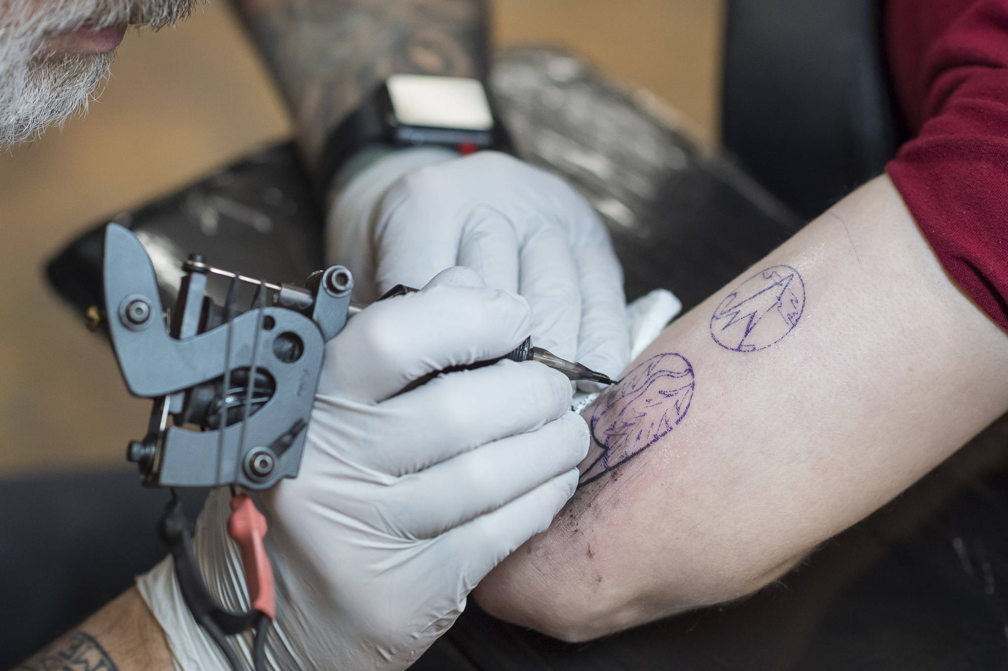 Tattoo artist Mario Singh applies a stylized semicolon to the back of Amy Ridle’s upper arm at Taku Tattoo on Monday, Nov. 19, 2018. (Michael Penn | Juneau Empire)