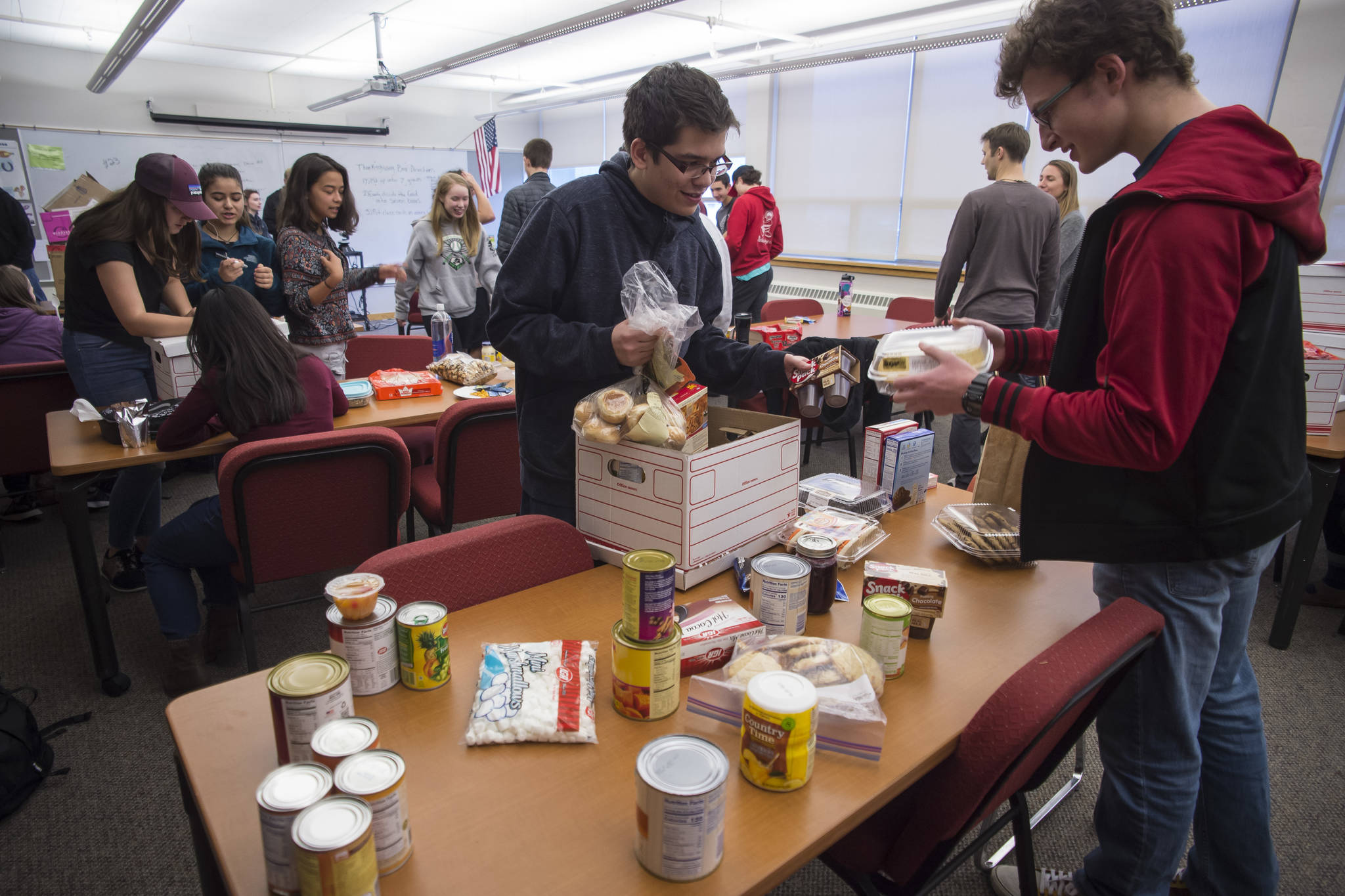 Juneau-Douglas High School senoirs Ramiro Garcia and Steven Ireland-Haight, right, fill a box with Thanksgiving dinner to be donated to AWARE and The Glory Hall on Tuesday, Nov. 20, 2018. The JDHS chapter of Sources of Strength, a nationwide organization that promotes positivity in schools donated seven boxes to the organizations. Students from every homeroom contributed food. (Michael Penn | Juneau Empire)