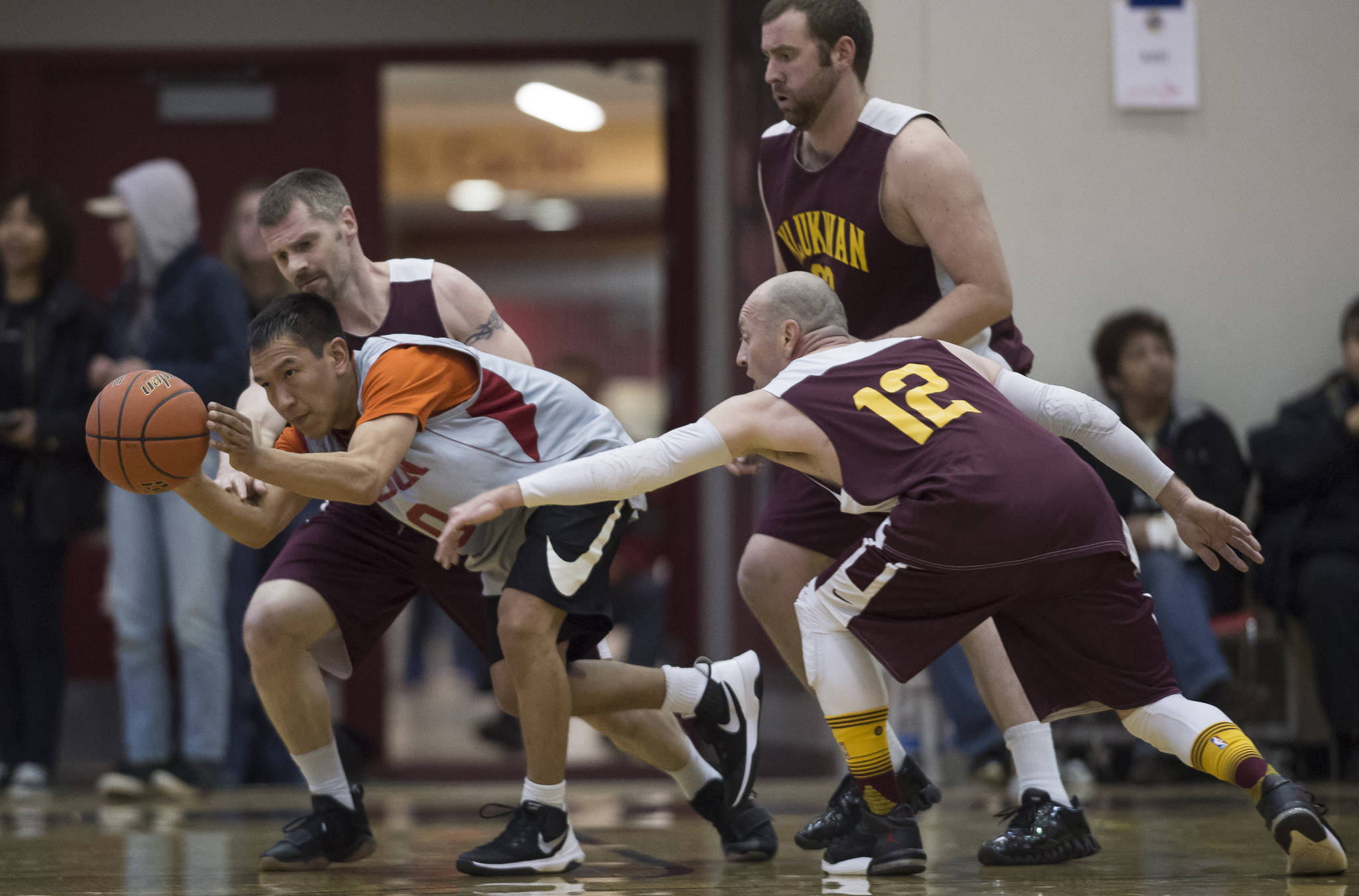 Angoon’s Curtis Lane passes away from Klukwan’s Michael Ganey and Jason Shull in the C bracket final at the Juneau Lion’s Gold Medal Basketball Tournament at Juneau-Douglas High School on Saturday, March 24, 2018. (Michael Penn | Juneau Empire File)