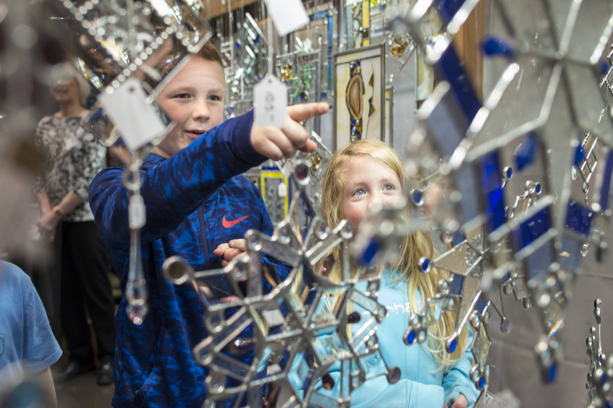 Tayt Whiteley, 8, and his sister, Delilah, 5, admire the stained glass snowflakes by Connie Nesgoda at the Public Market in Centennial Hall on Friday, Nov. 23, 2018. (Michael Penn | Juneau Empire)