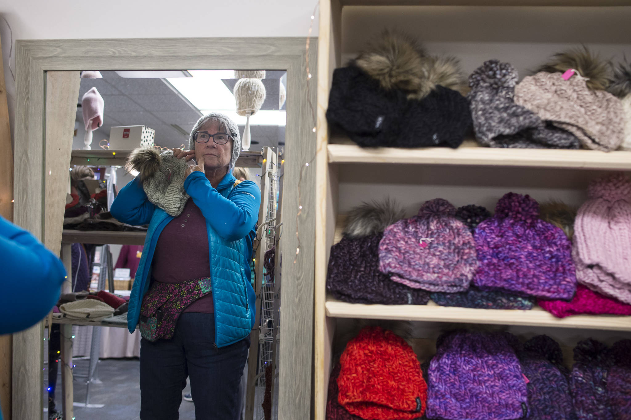 Carol Bruce tries on a hat at the W.W. Knits booth at the Public Market in Centennial Hall on Friday, Nov. 23, 2018. (Michael Penn | Juneau Empire)