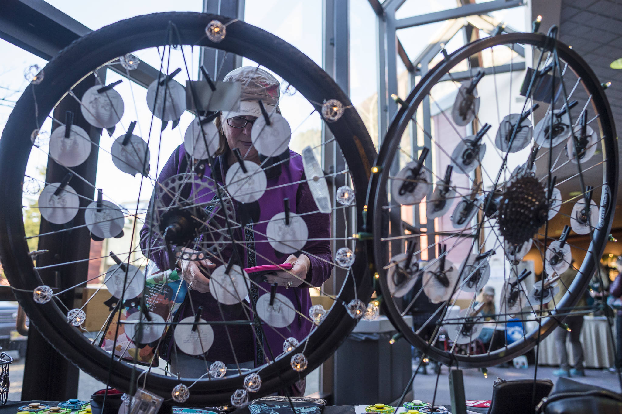 Timi Tullis looks at jewelry made of bicycle parts by Deb Winkelman at the Public Market in Centennial Hall on Friday, Nov. 23, 2018. (Michael Penn | Juneau Empire)