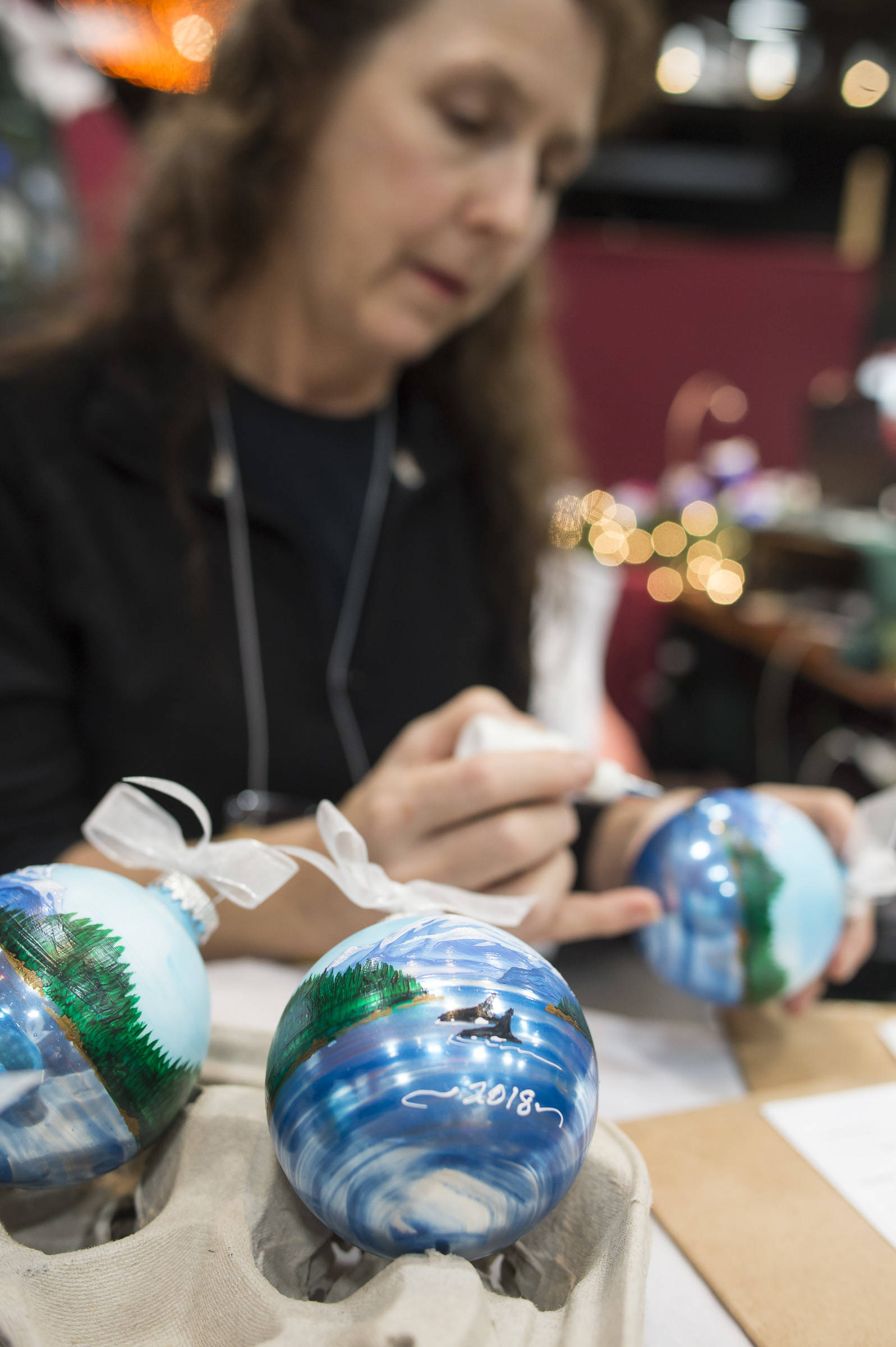 Cindy Wortman-Ziel hand paints Christmas ornaments at the Public Market in Centennial Hall on Friday, Nov. 23, 2018. (Michael Penn | Juneau Empire)