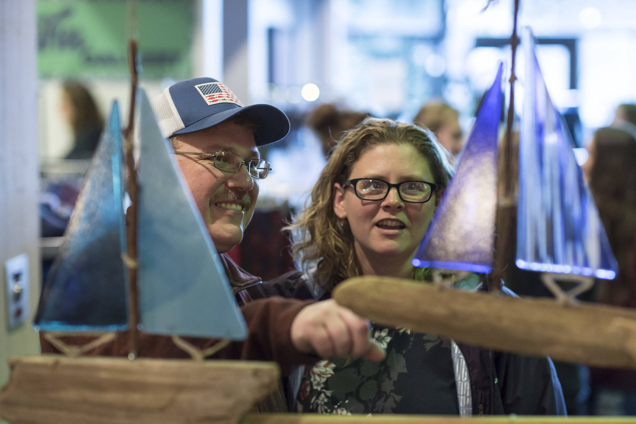 Tyler and Sarah Eddy, of Sitka, admire sailboats on display by Darcie Henderson of Sea Glass Designs at the Public Market in Centennial Hall on Friday, Nov. 23, 2018. (Michael Penn | Juneau Empire)