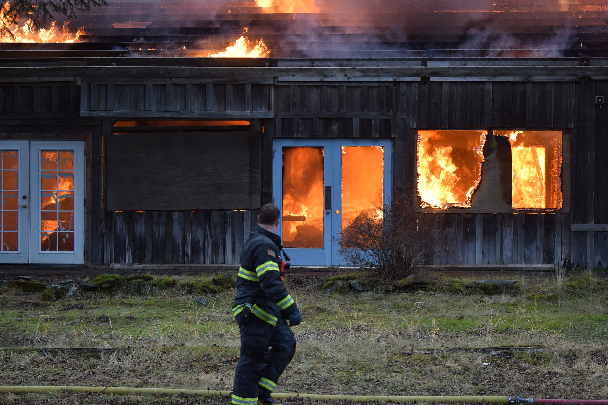 A Capital City Fire/Rescue firefighter walks past the backside of the Thane Ore House during a live fire training exercise on Saturday, Nov. 24, 2018. (Nolin Ainsworth | Juneau Empire)