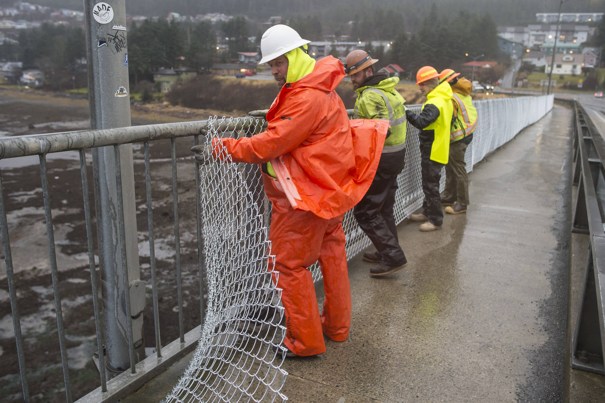 A crew from the Department of Transportation and Public Facilities installs chain-link fencing along the pedestrian walkway over the Douglas Bridge on Monday, Nov. 26, 2018. (Michael Penn | Juneau Empire)