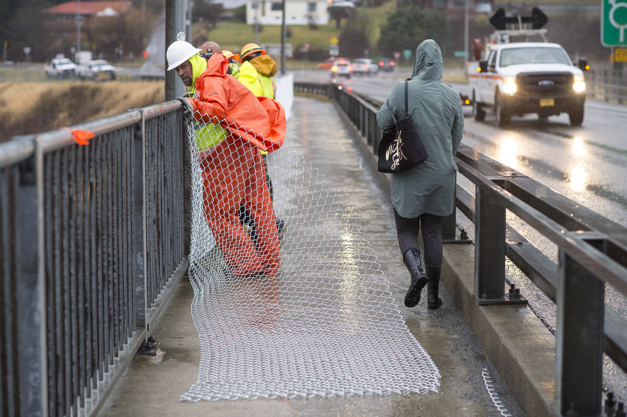 A crew from the Department of Transportation and Public Facilities installs chain-link fencing along the pedestrian walkway over the Douglas Bridge on Monday, Nov. 26, 2018. (Michael Penn | Juneau Empire)
