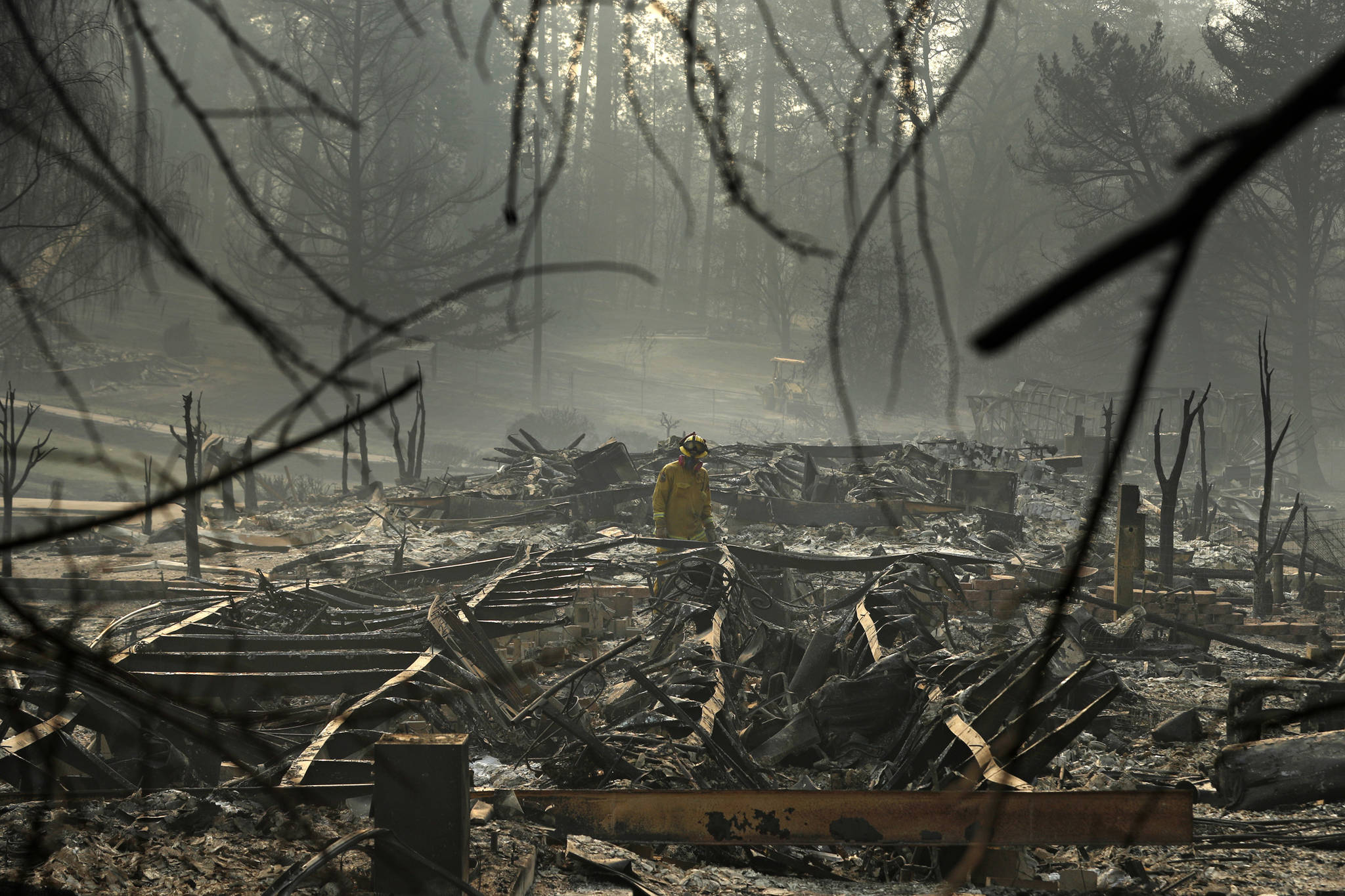 In this Nov. 16, 2018 photo, a firefighter searches for human remains in a trailer park destroyed in the Camp Fire, in Paradise, California. The massive wildfire that killed dozens of people and destroyed thousands of homes has been fully contained after burning for more than two weeks, authorities said Sunday, Nov. 25. (John Locher | Associated Press File)