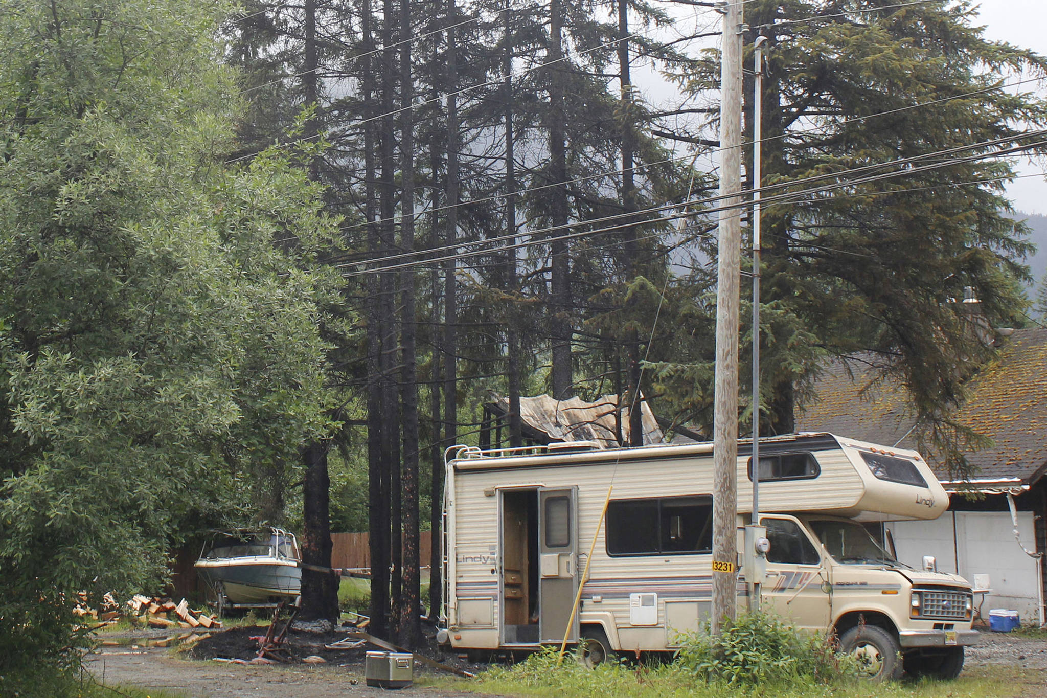 Charred trees rise above a burnt motor home and shed at a Mendenhall Valley home on July 10, 2018. An early-morning fire damaged the shed, the motor home, a fish smokehouse and a Chevy truck. (Alex McCarthy | Juneau Empire File)