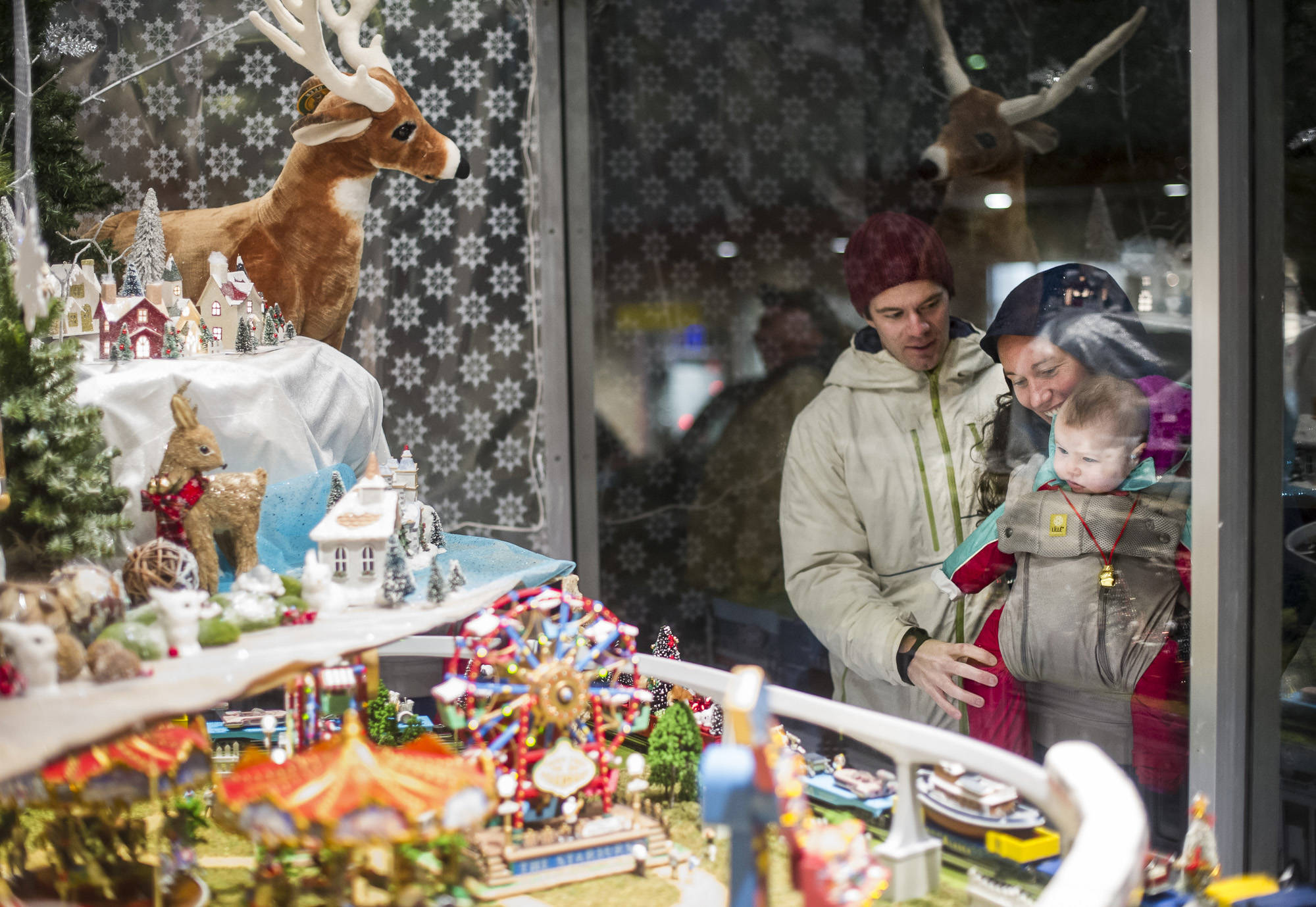 Kim McNamara and Paul Hackenmueller show their new daughter, Opal, the Christmas window at REACH during Gallery Walk on Friday, Dec. 2, 2016. (Michael Penn | Juneau Empire File Photo)