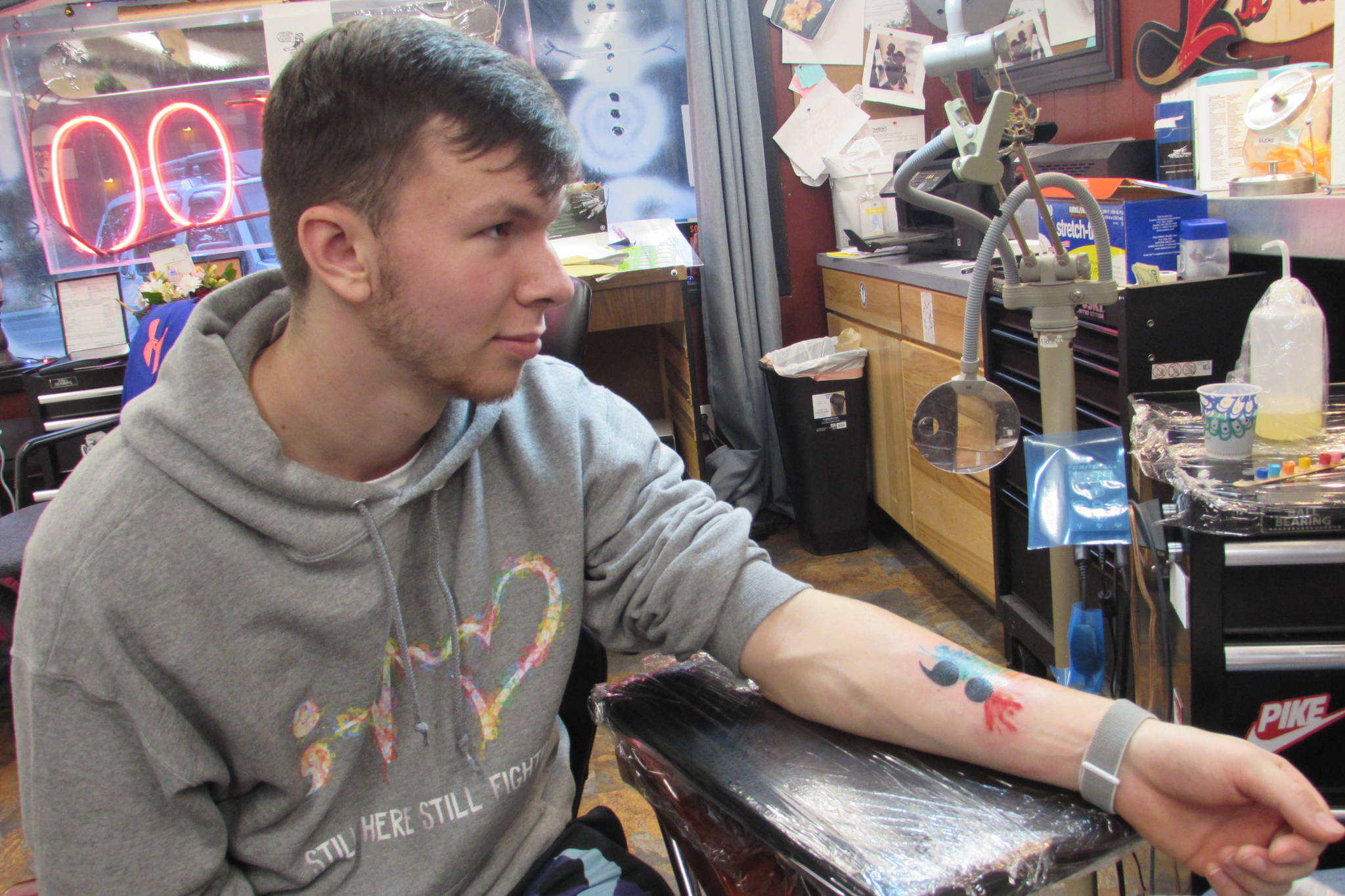 Jonathan Funk was happy with his first-ever tattoo. The semicolon’s water color color splashes were similar to the design on the hoodie he wore. (Ben Hohenstatt | Capital City Weekly)