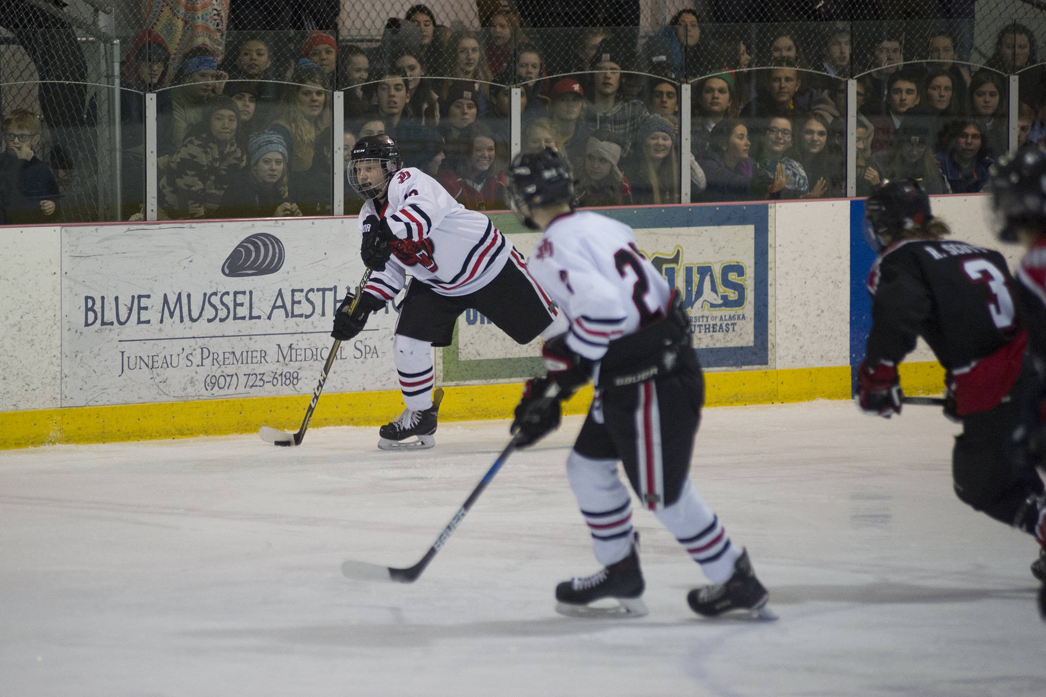 Juneau-Douglas’ Kyler Alderfer makes a pass up the ice while Tyler Weldon gets in position against Houston on Friday. JDHS won 7-0. (Nolin Ainsworth | Juneau Empire)