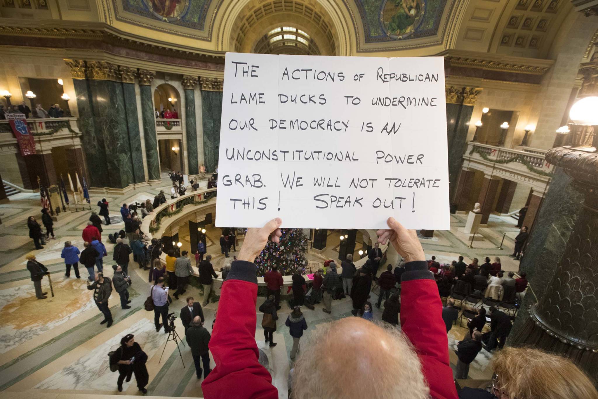 People protest the legislature’s extraordinary session during the official Christmas tree lighting ceremony at the Capitol in Madison, Wisconsin on Tuesday, Dec. 4, 2018. Demonstrators booed outgoing Wisconsin Gov. Scott Walker on Tuesday during the Christmas tree-lighting ceremony, at times drowning out a high school choir with their own songs in protest of a Republican effort to gut the powers of his Democratic successor. (Mark Hoffman | Milwaukee Journal-Sentinel)