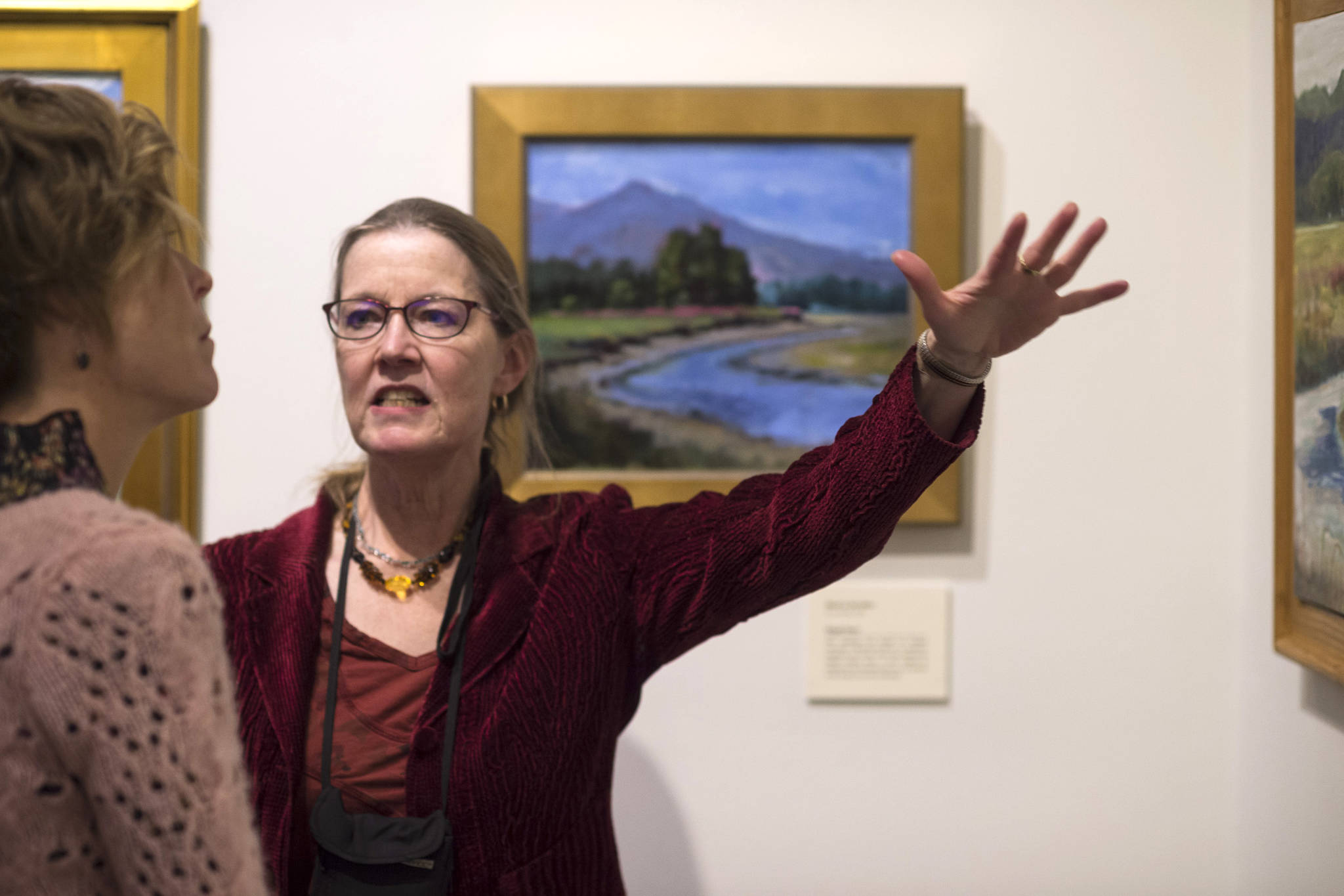 Timi Johnson talks about the Plein Rein Painters work inspired by Sydney Lawurence at the Juneau-Douglas City Museum during Gallery Walk on Friday, Dec. 7, 2018. (Michael Penn | Juneau Empire)